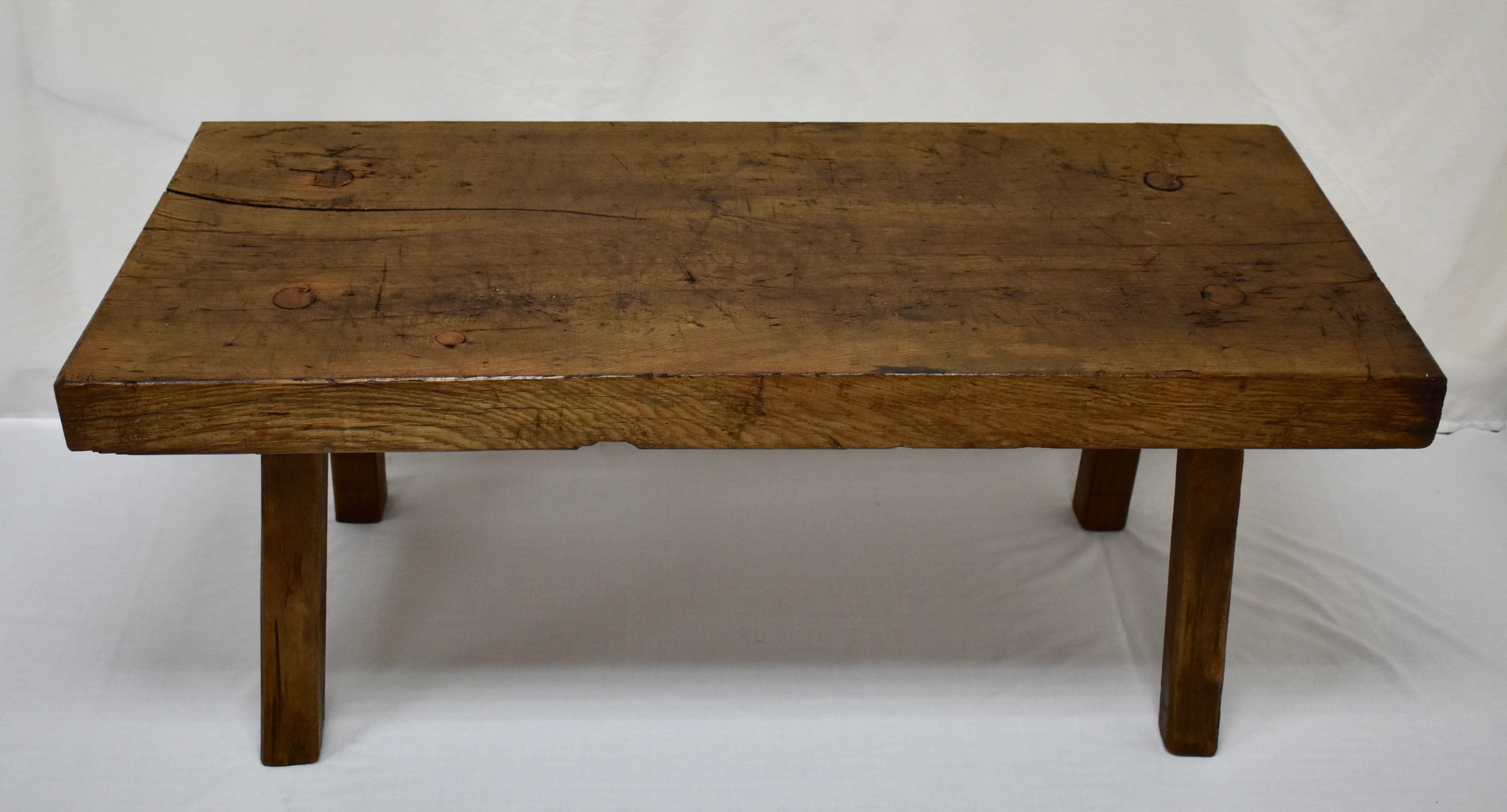 This handsome butcher’s block low table stands on four splayed legs over 2” square which are through-tenened and wedged into the underside of the top. The top itself is a single oak slab over 3” thick with scratches, scrapes, and dings indicating