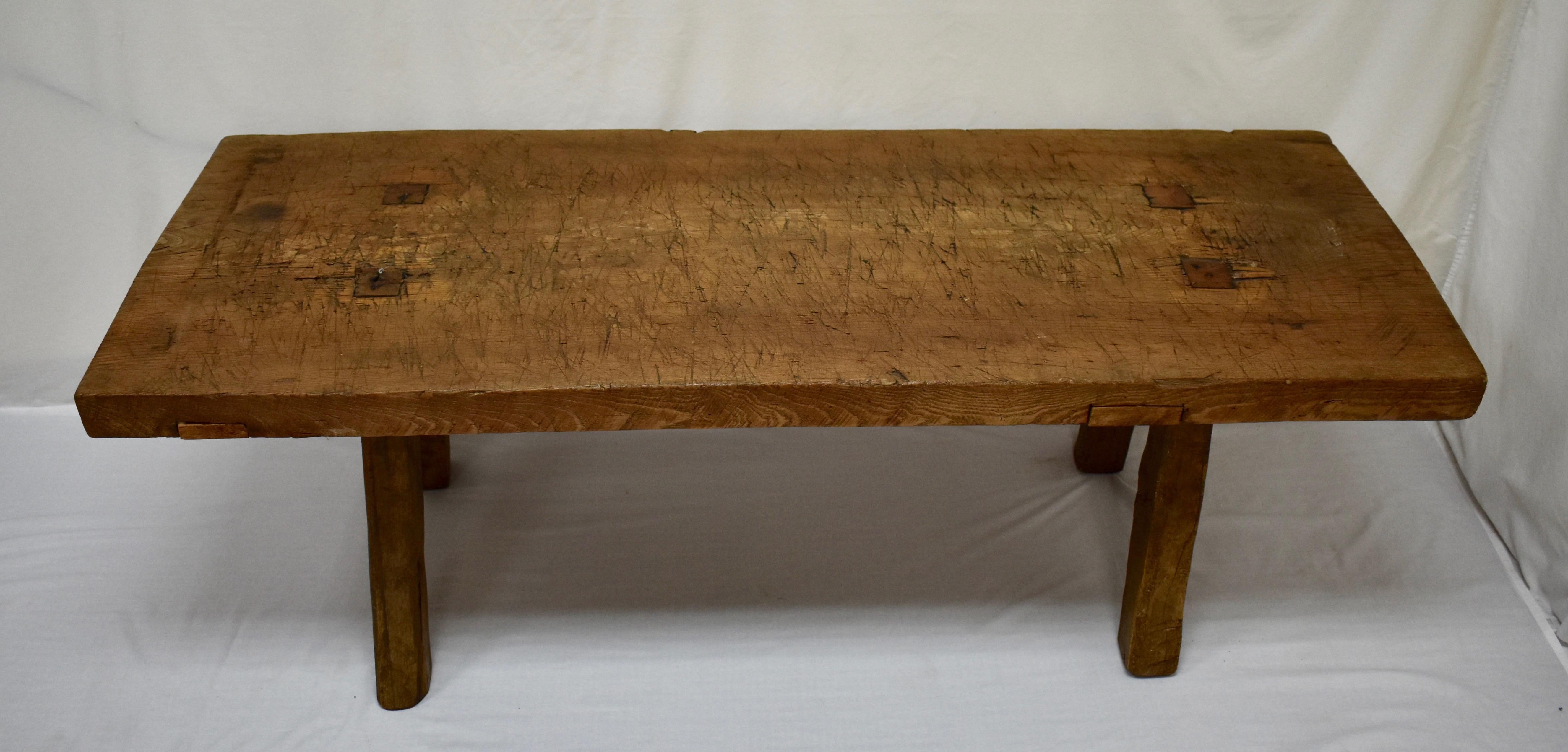 A superb oak pig bench coffee table standing on four sturdy, splayed, hand-hewn legs, which are through-tenoned and wedged into the underside of the top. The top itself is a single oak slab 2.5” thick, which is chopped, scratched and gnarled through