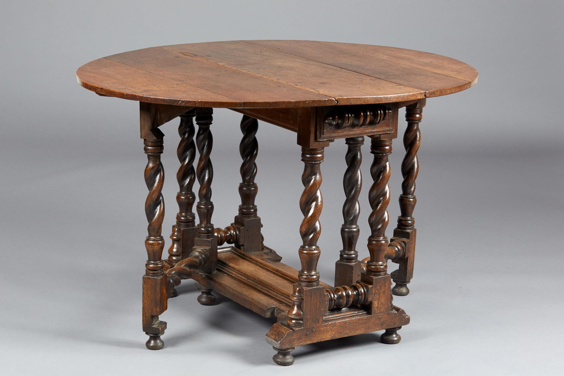 Rare Charles II / William & Mary oak gate leg table, English, circa 1670-1690.

The oval plank top above multi spiral twist legs with twin concealed action frieze drawers with applied split balusters, on a platform base with raised cushion
