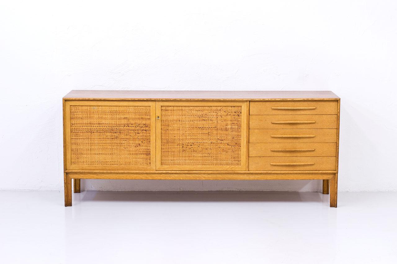 “Norrland” sideboard, large version designed by Alf Svensson for Bjästa Möbelfabrik. 
Dated 12 February 1962.
Made from oak with two doors panel covered by rattan webbing. 
Inside in birch with adjustable shelves. 
Stamped by maker.