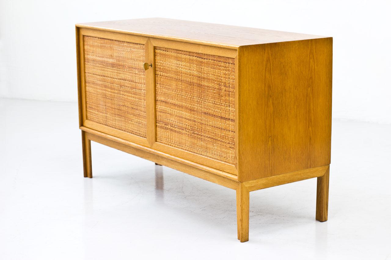 Sideboard  designed  by Alf  Svensson
manufactured by Bjästa Möbelfabrik in
Sweden  during the 1960s.  Made  from
oak  with two doors panel covered  by
rattan  webbing.  Brass key.   Inside  in
birch with adjustable shelves.   Signed
by maker. 