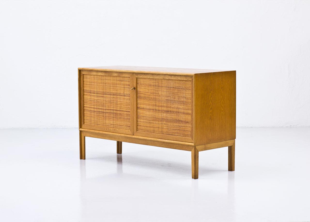 Sideboard designed by Alf Svensson
manufactured by Bjästa Möbelfabrik in
Sweden during the 1960s. Made from
oak with two doors panel covered by
rattan webbing. Brass key. Inside in
birch with adjustable shelves. Signed
by maker.