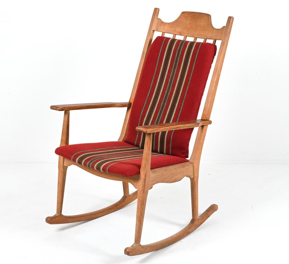 Crafted from gorgeous quarter-sawn white oak, this rare high-back rocking chair was designed by the legendary and enigmatic architect Henning Kjærnulf for the Danish furniture maker EG Kvalitetsmøbel in the 1970's. The crest rail features a subtle