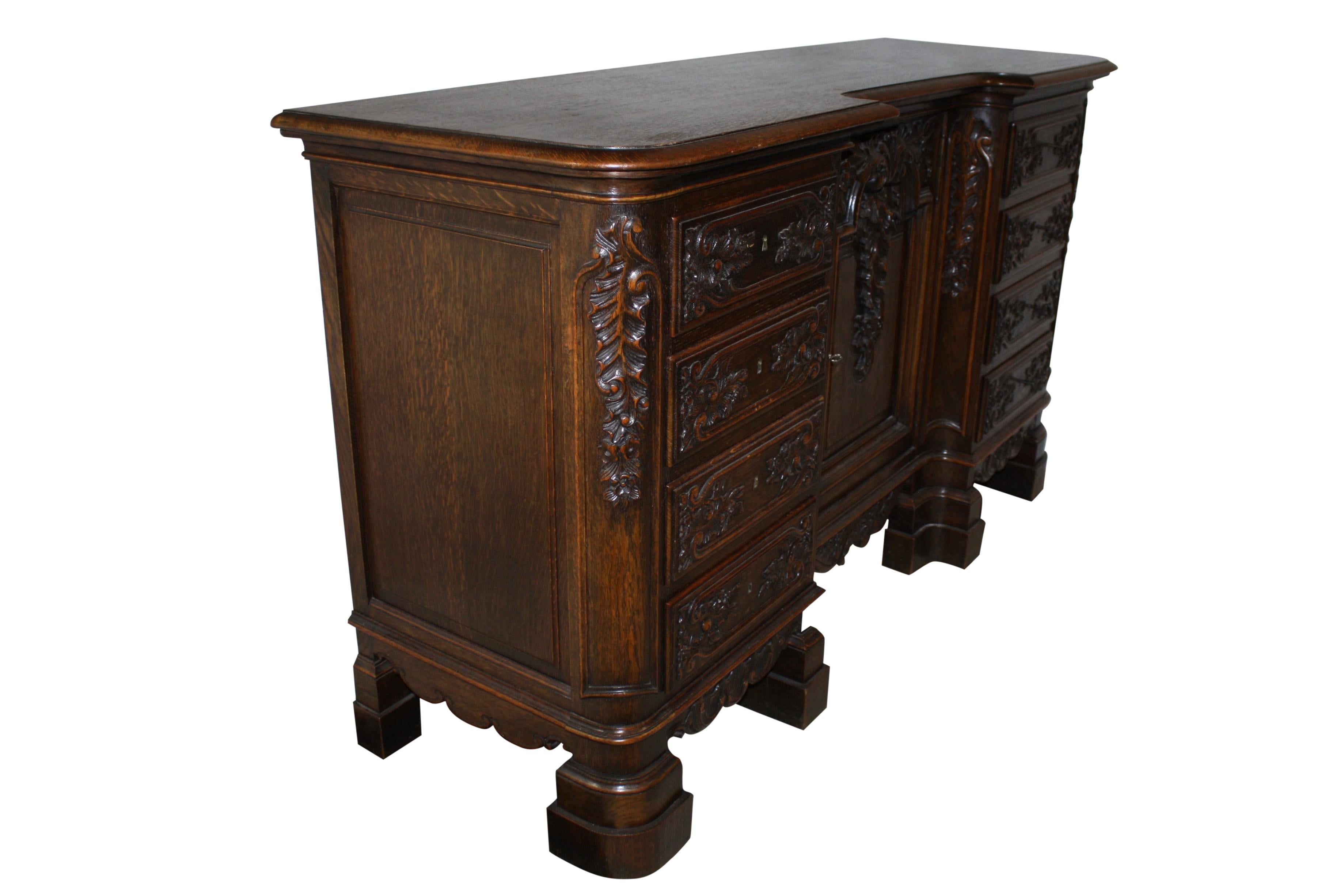 Featuring reverse breakfront construction with a set back center, this stunning server showcases foliated carvings with dainty flowers, C scrolls, and ribbon. The center door, which opens to two shelves, is flanked by four drawers on each side. The