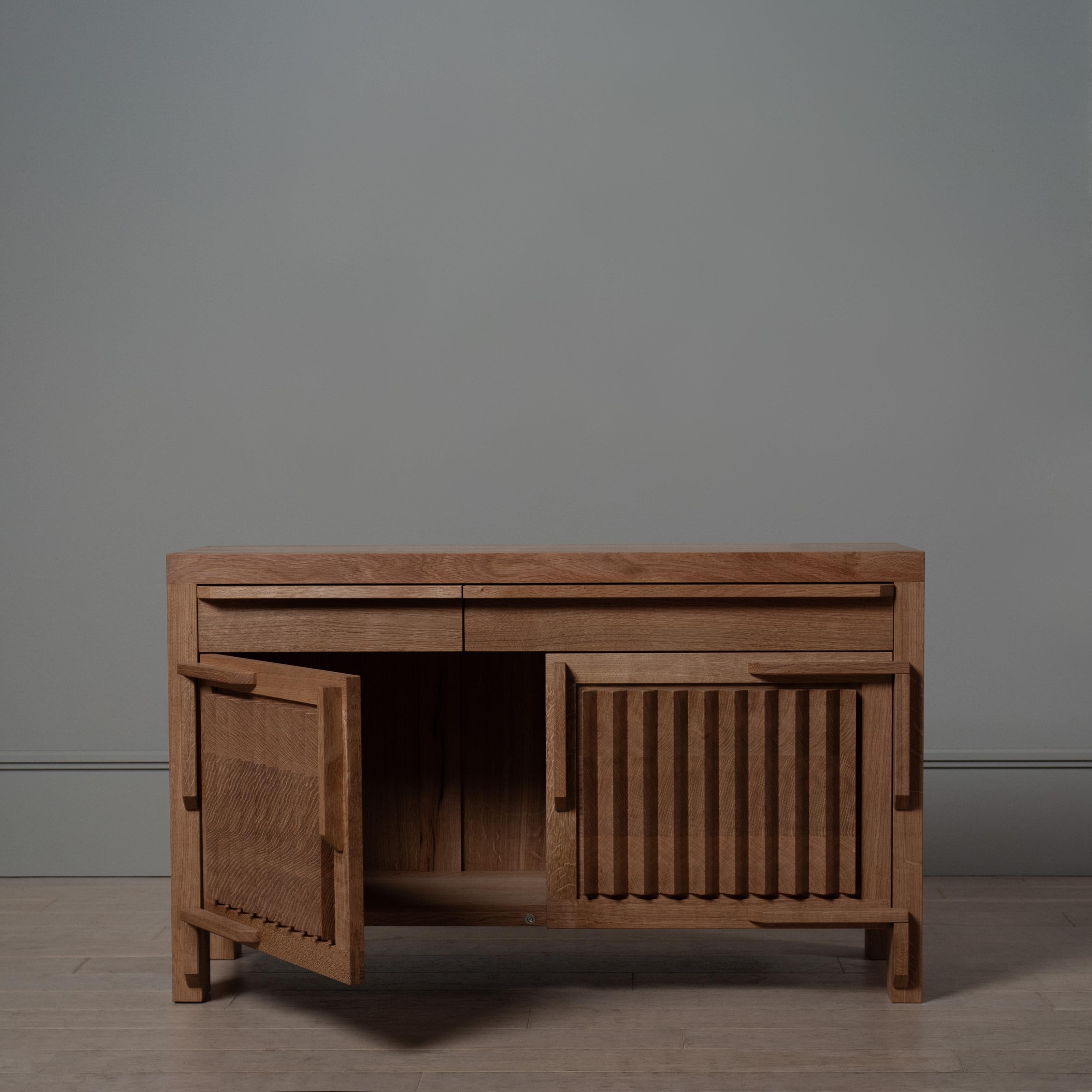 Questo imponente mobile/seduta a dente di sega mette in mostra la splendida quercia e la maestria artigianale. 
Piuttosto che scusarsi per l'hardware proprietario, James fa un'ottima figura con le cerniere in legno realizzate in officina. Le