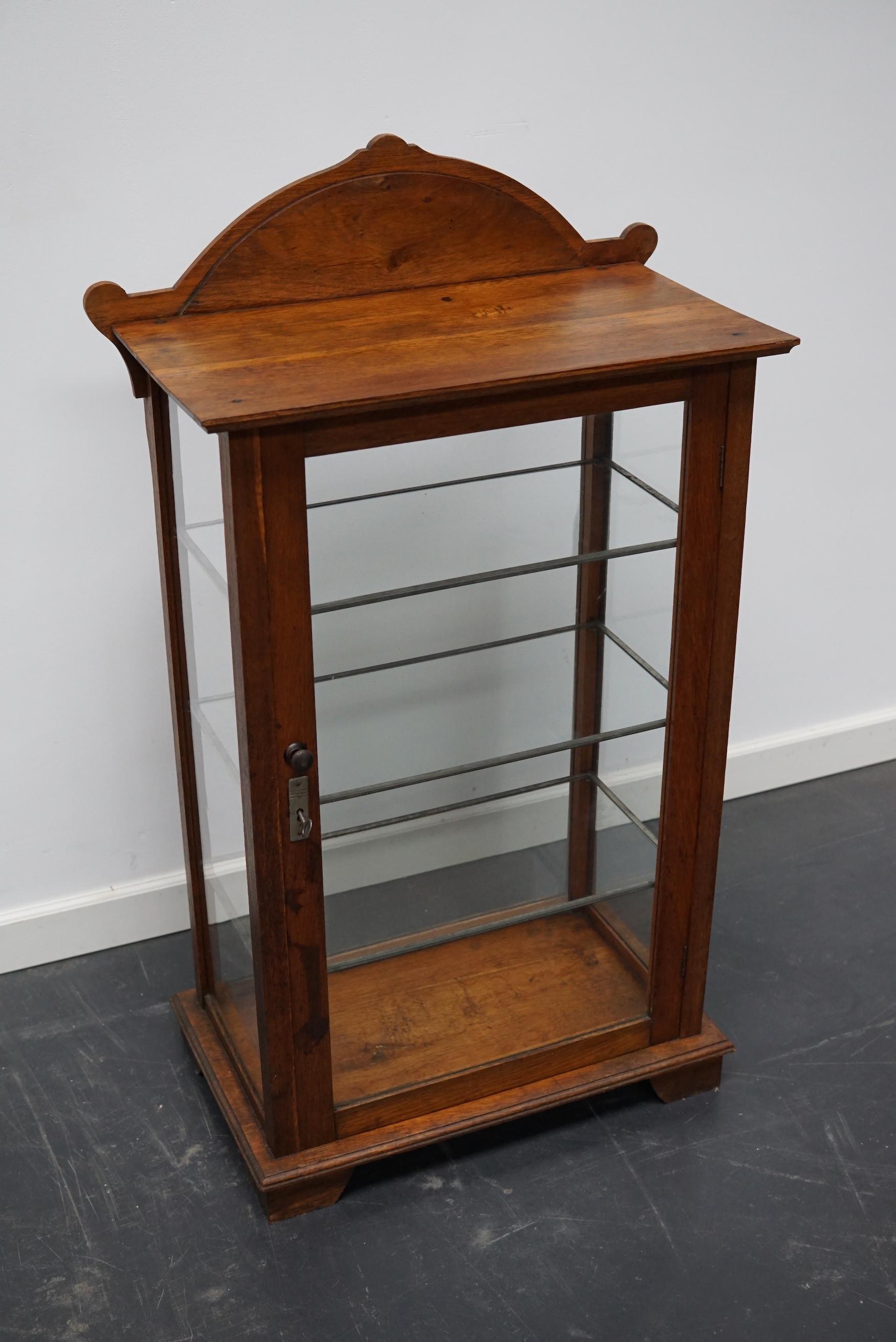 Diese Vitrine ist aus Eichenholz gefertigt, das Glas ist mit Blattgold beschriftet, auf der Vorderseite steht oben Schlieper. Der Schrank hat eine Tür auf der Rückseite und drei Glasböden. Dies ist ein sehr attraktives und nützliches Stück und es