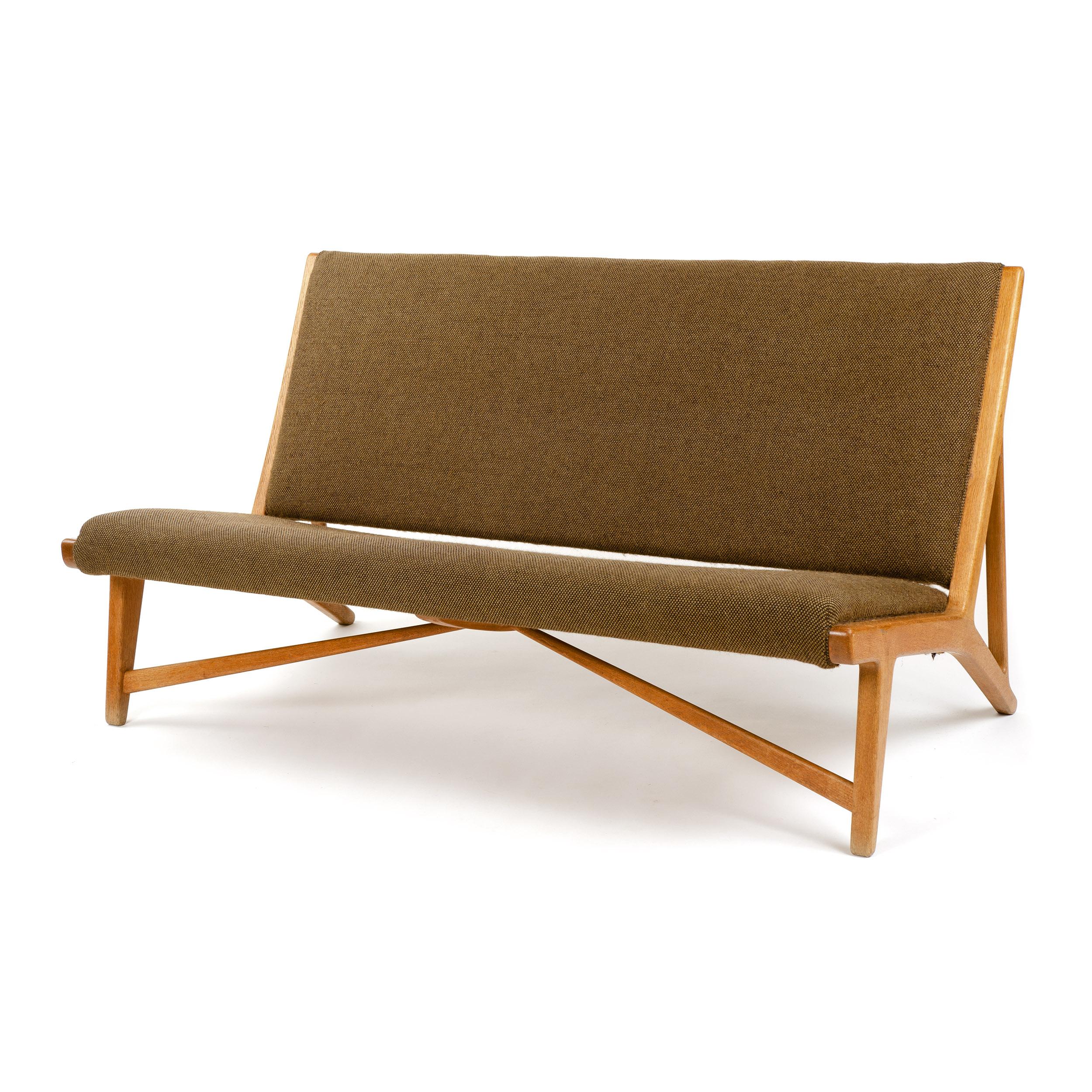 An oak bench, settee or sofa with diagonal tapered leg trusses, retaining the original green/brown wool upholstery. Designed by Hans Wegner circa 1949, manufactured by Johannes Hansen in Denmark, circa 1950s. 

Model JH-555.
 