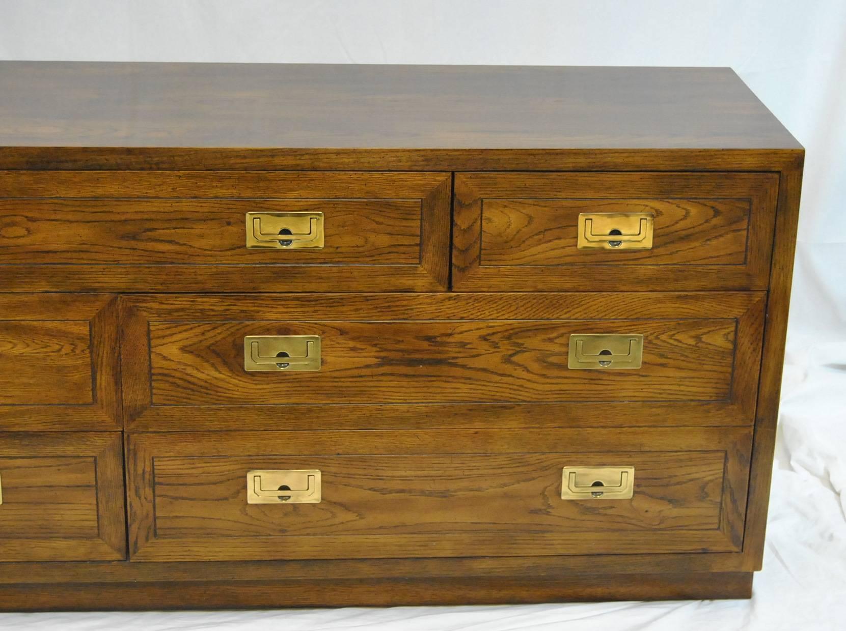 A great campaign style seven-drawer oak dresser by Henredon. This is part of their scene I collection and has clean campaign styling with heavy inset brass pulls. Two of the larger drawers are divided for organization of contents. This is 72