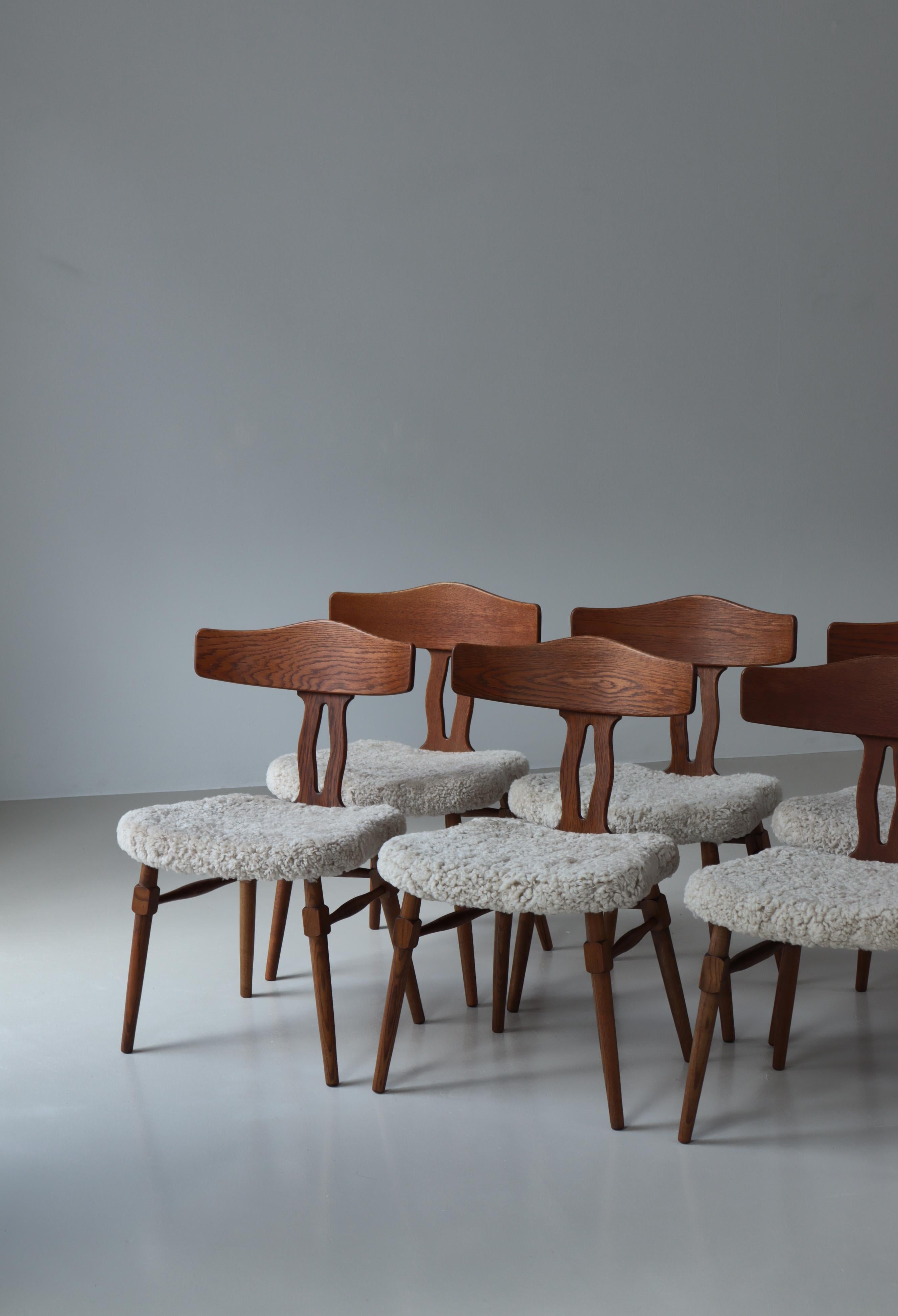 Bellissimo set di 6 sedie da pranzo del designer danese Henry Kjærnulf realizzato negli anni '50 in Danimarca. Le sedie sono realizzate in legno di quercia massiccio con una bella venatura e patina. Sono state rivestite con una spessa pelle di