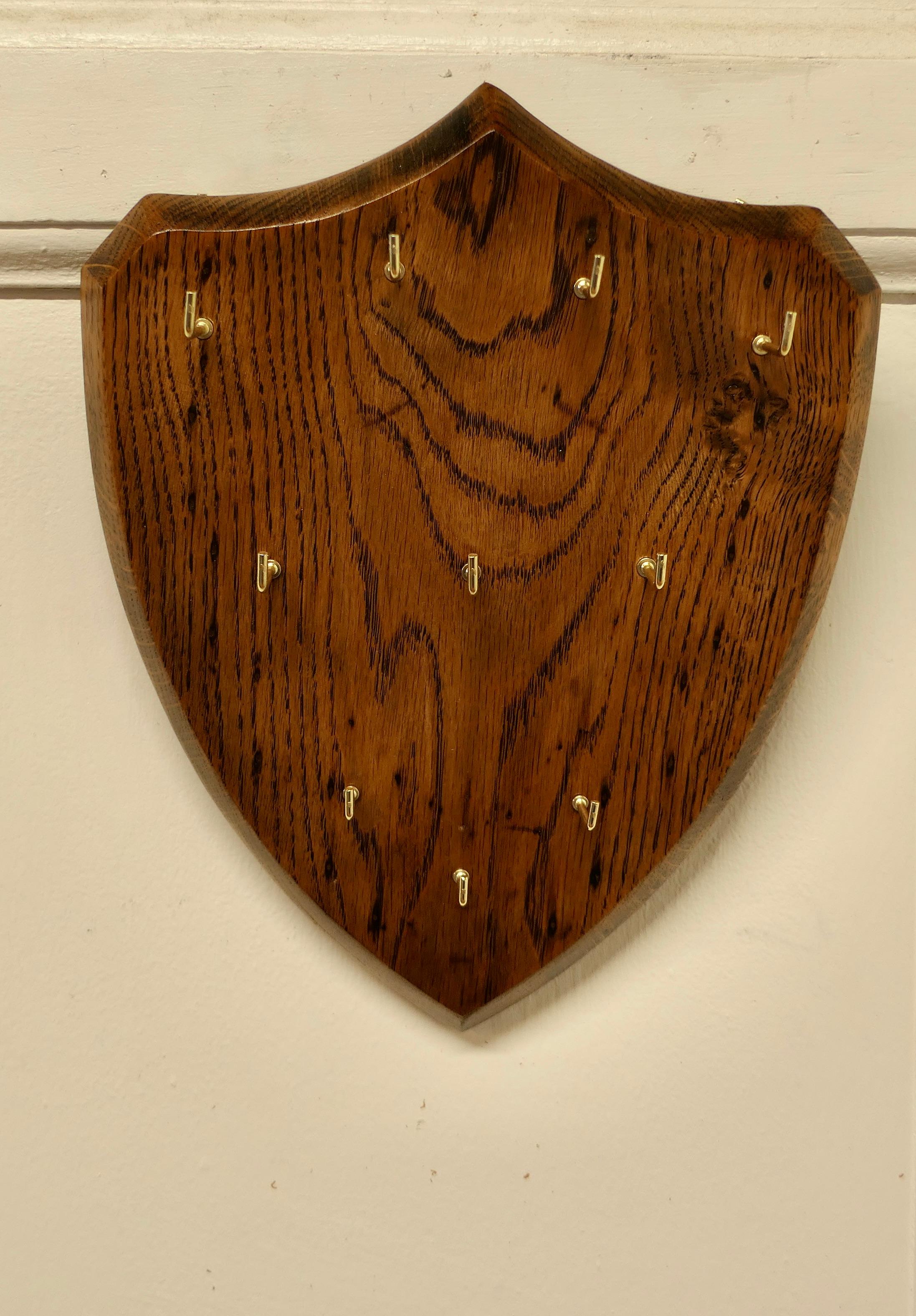 Oak Shield Hotel Reception Key Board 

This is a Solid Oak Key board in the shape of a shield, it has 10 key hooks on the front, the rack can be wall hung
The rack is in good condition, it is 11” high 9” wide and 2” deep
TCC77.