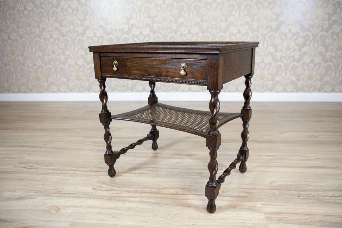 Oak Side Table From the 1930s in Dark Brown

An oak table from the Interwar Period, supported by spiral legs, reinforced in the middle with a rattan shelf, and with crosswise spiral connections at the bottom. The tabletop has an edge finished with a