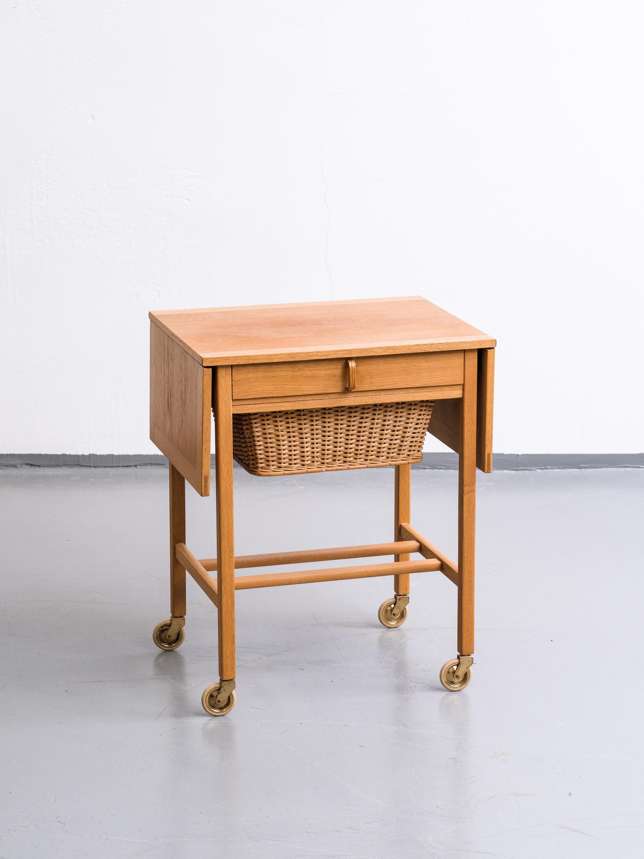 Oak side table with rattan basket and drop-down leafs. Width 58-108 cm. Bertil Fridhagen for Bodafors, 1960s. Stamped.