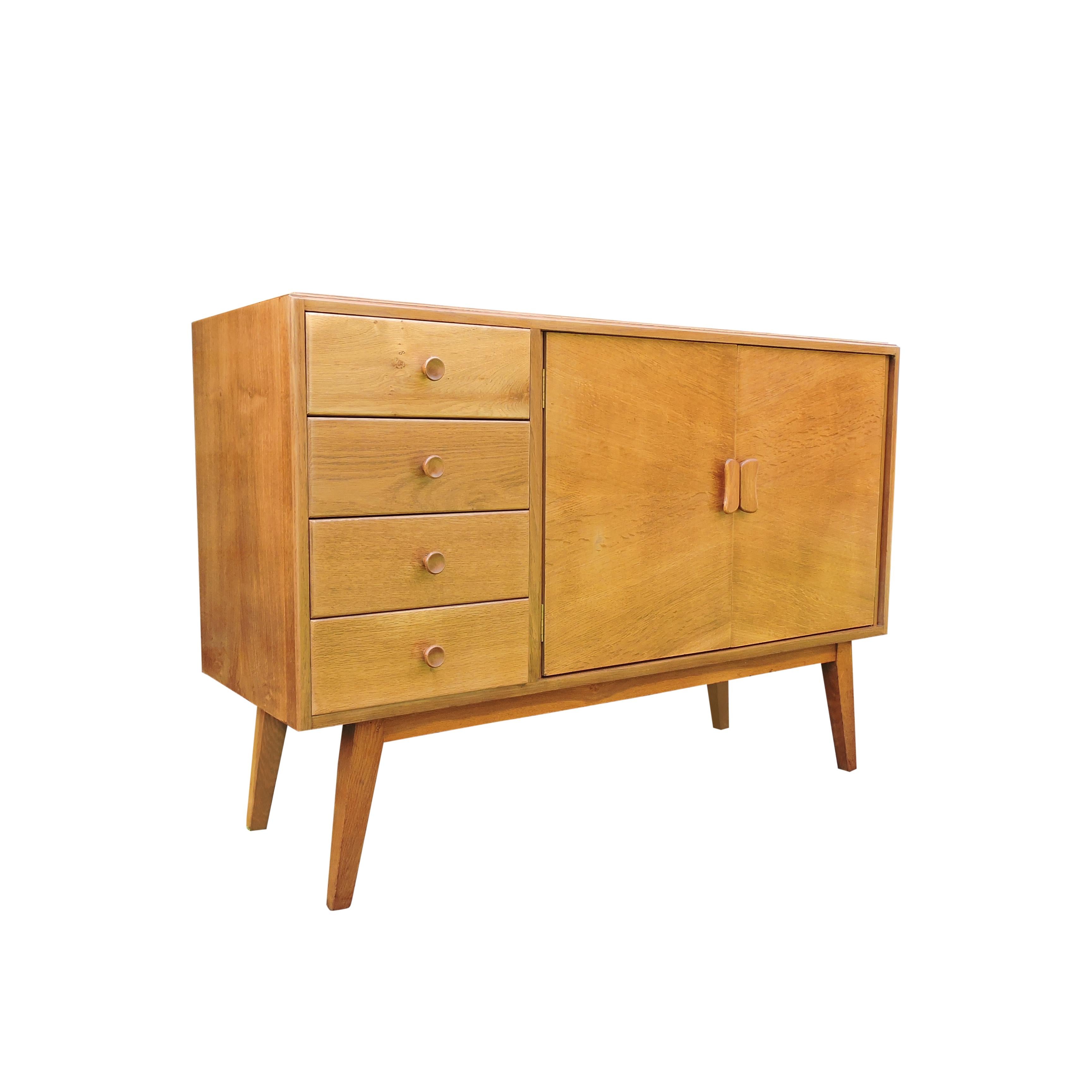 An early oak sideboard manufactured in the 1950s. The sideboard stands on splayed squared legs.