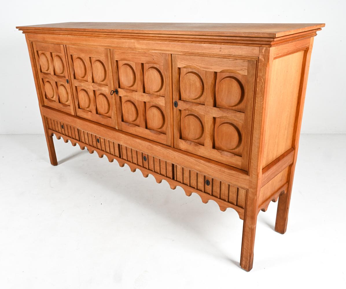 This classic sideboard has been designed by Henry 'Henning' Kjaernulf, who is known for his famous Brutalist technique and timeless mid-century modern style. Crafted in beautiful oak wood and with intricately carved decoration on the front panels