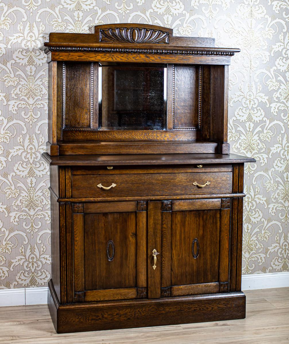 Massive Oak Sideboard from the Interwar Period with Mirror

We present you an oak sideboard from the Interwar Period.
This piece of furniture is composed of a two-leaf base, with a drawer under the top on its whole width, and a sliding panel.
The