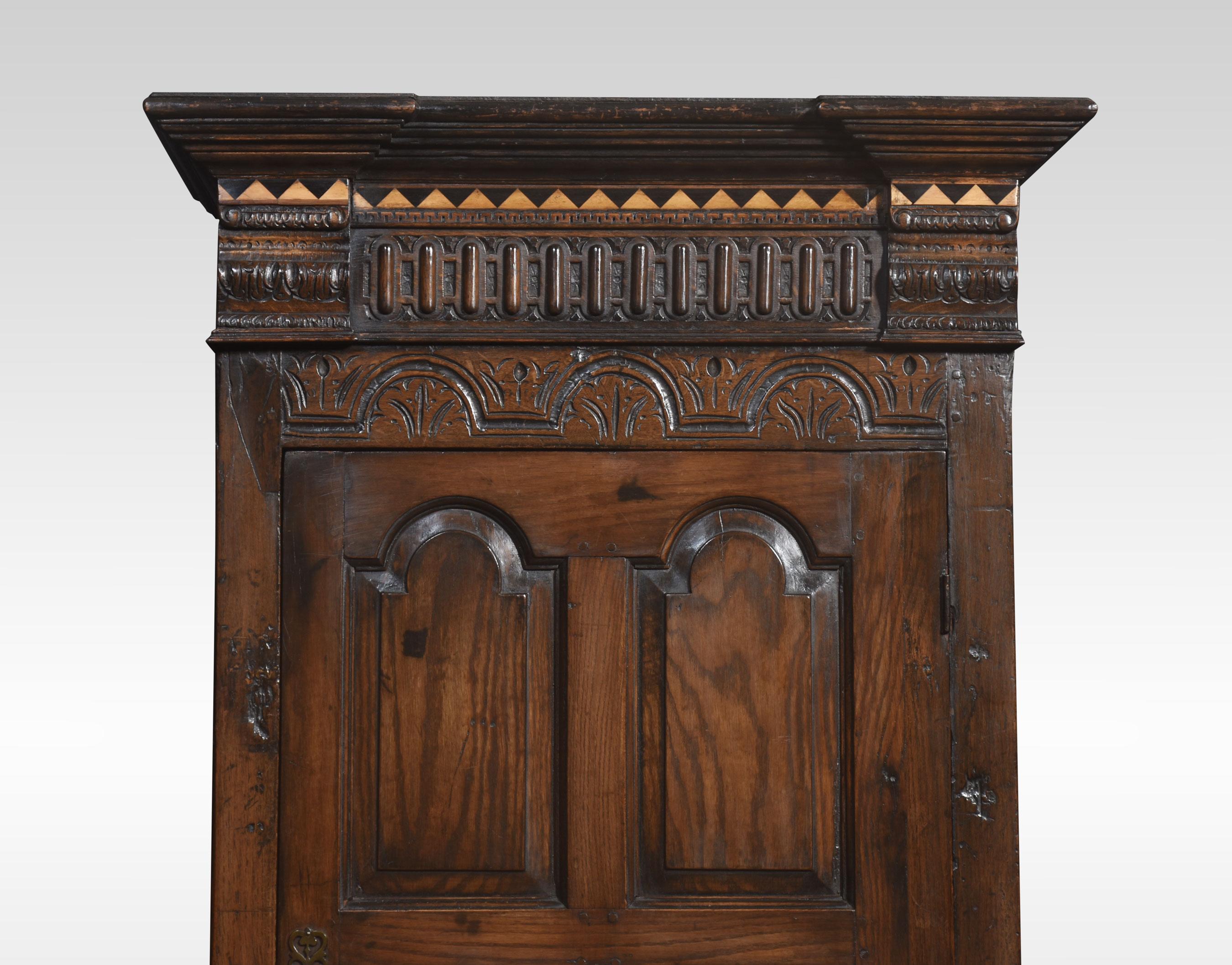 Eintüriger Kleiderschrank aus Eiche im Stil des 17. Jahrhunderts, mit umgedrehtem Gesims über geschnitzten Details. Die große eichengetäfelte Tür öffnet sich und gibt den Blick auf einen großen Hängebereich frei. Alle stehen auf