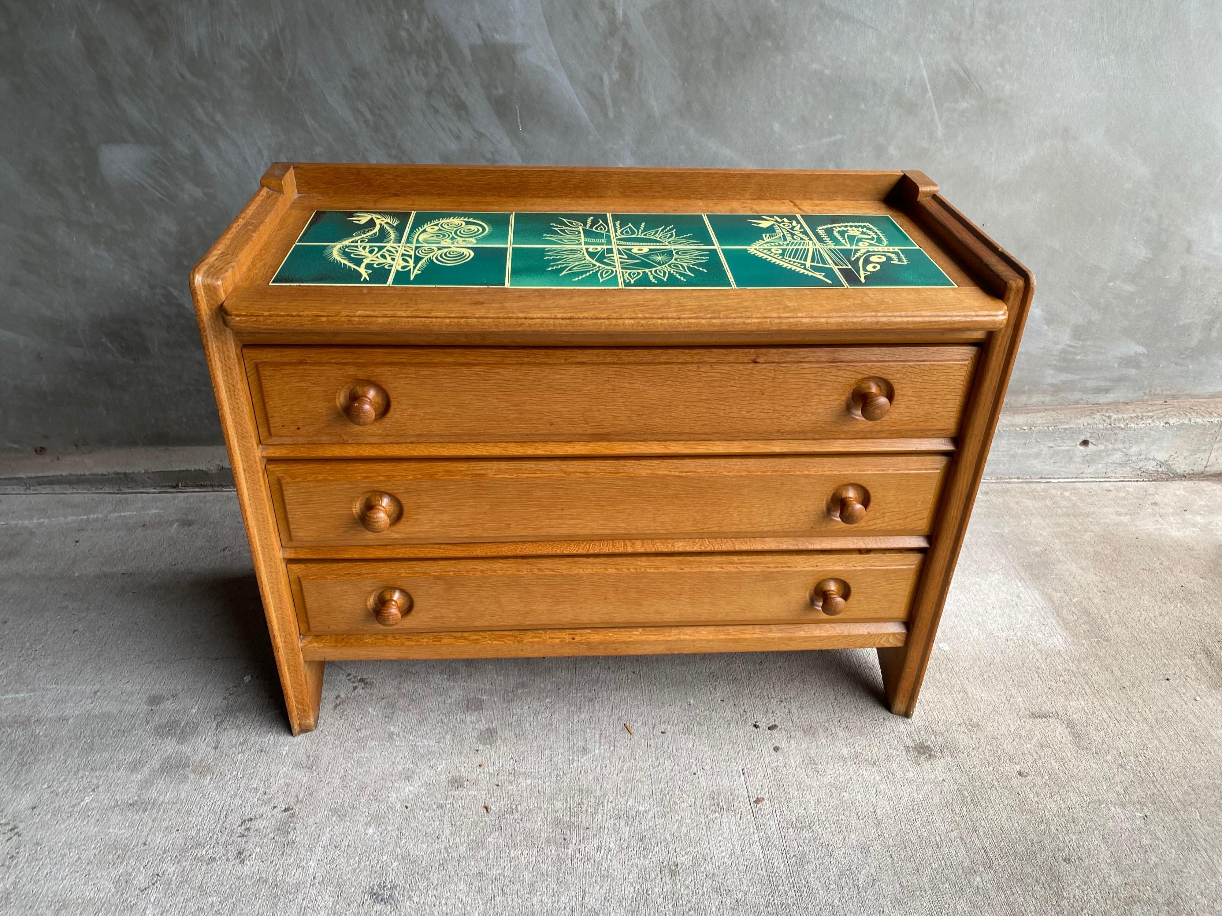 Chest of drawers by collectible design duo, Guillerme & Chambron, in French oak and from their studio, Votre Maison. Decorative green ceramic tile top by their friend and frequent collaborator, Boleslaw Danikowski. France, 1950's.