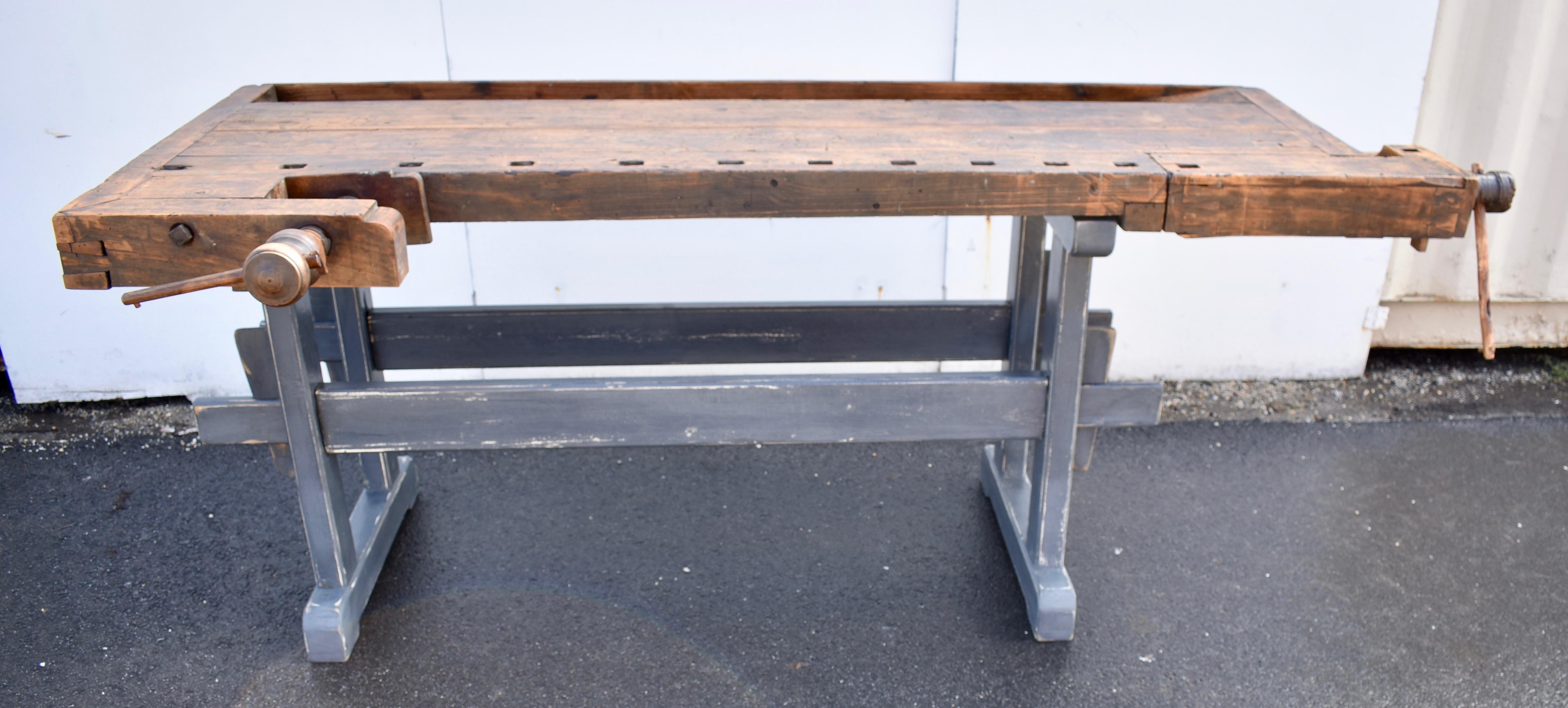 This is a beautifully chopped and gnarled carpenter’s workbench. 
The trestle-style base is made of oak and is possibly of later construction.  The uprights are hand-cut, through-tenoned and pegged top and bottom to the horizontal members. The