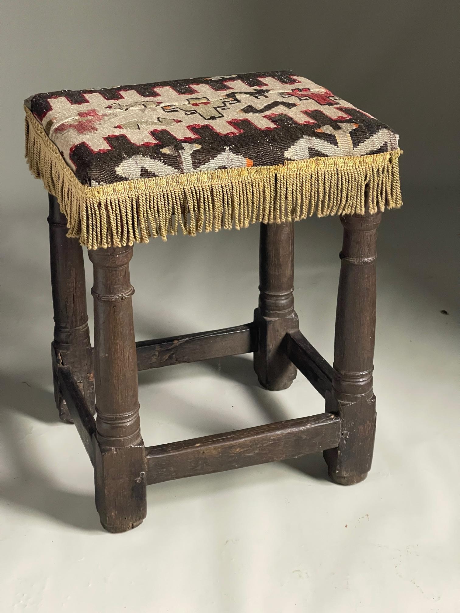 C1680 oak upholstered stool with turned legs and square section stretchers top upholstered with kilim rug

52 cms high 40 long 34 deep price
