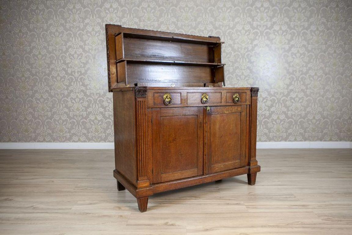 Oak Vanity Commode From the 19th Century in Brown

Vanity commode made of solid oak wood, dated to the early 19th century. A two-winged piece of furniture with three sub-drawer drawers, a double top connected by hinges, and additional pull-out tops