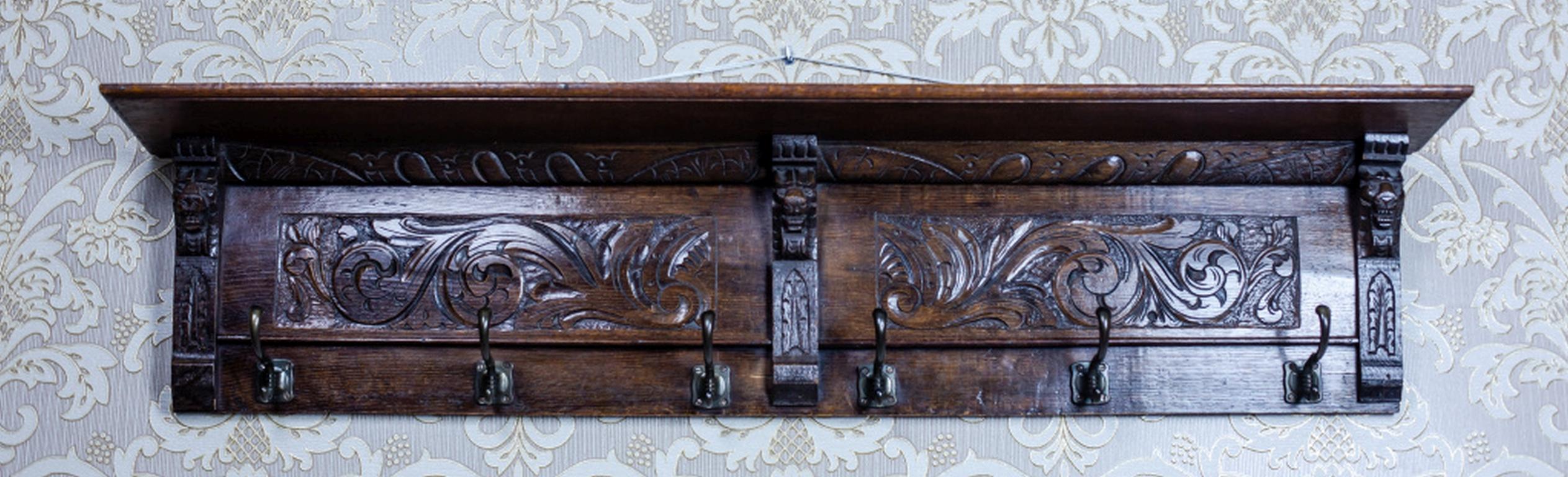 We present you a carved solid oak coat rack with metal hooks.
There are two rectangular fields on the rear wall of the coat rack which is covered with a carved decoration.
The whole is topped with an advanced cornice, which forms a