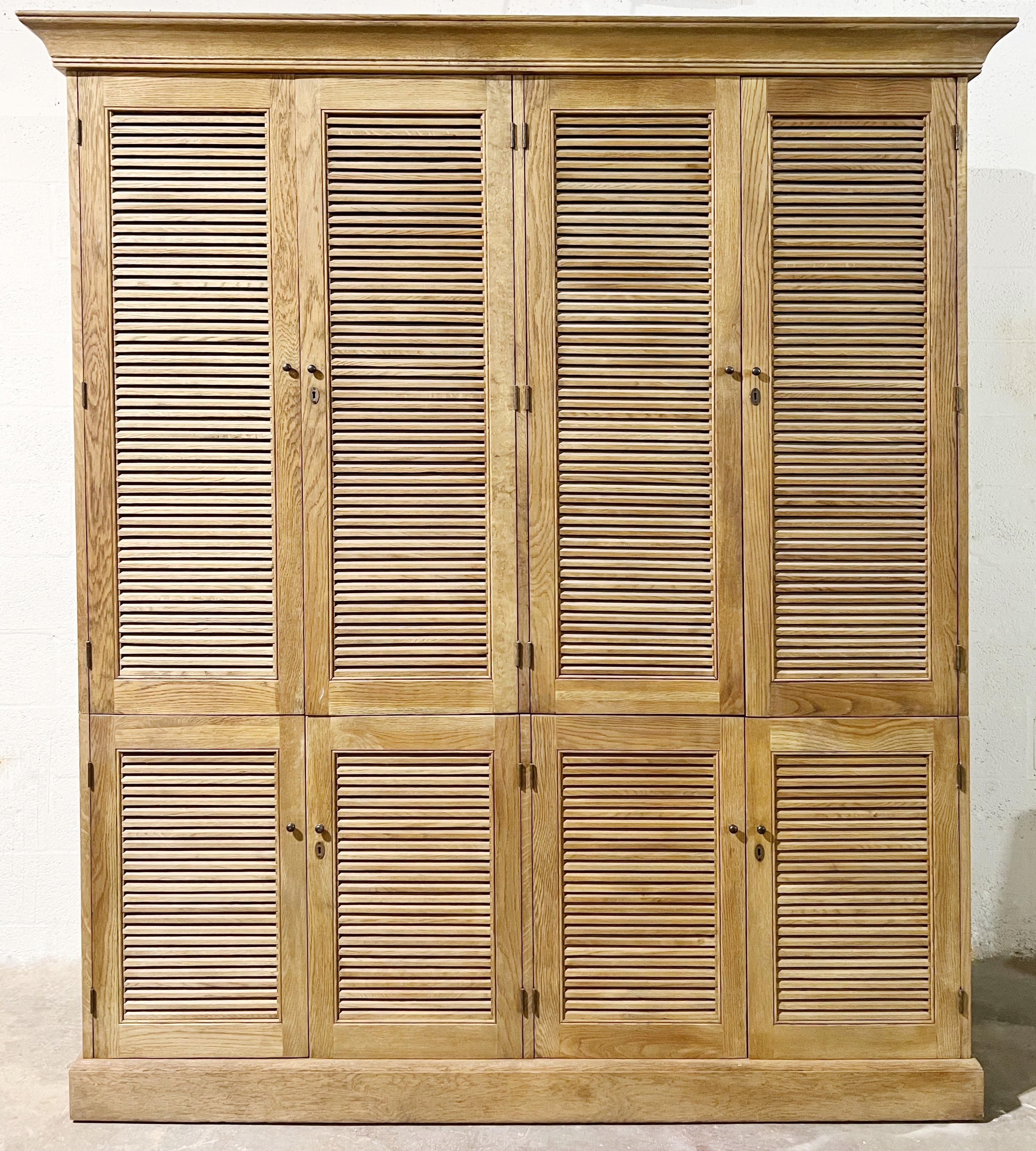 A large 2 piece wardrobe with doors with slatted design. 8 doors total. The bottom portion has 4 doors that reveal shelving. The top part accommodate shelving as well as rods for hanging. Beautifully made. Retains keys, shelves and rods.