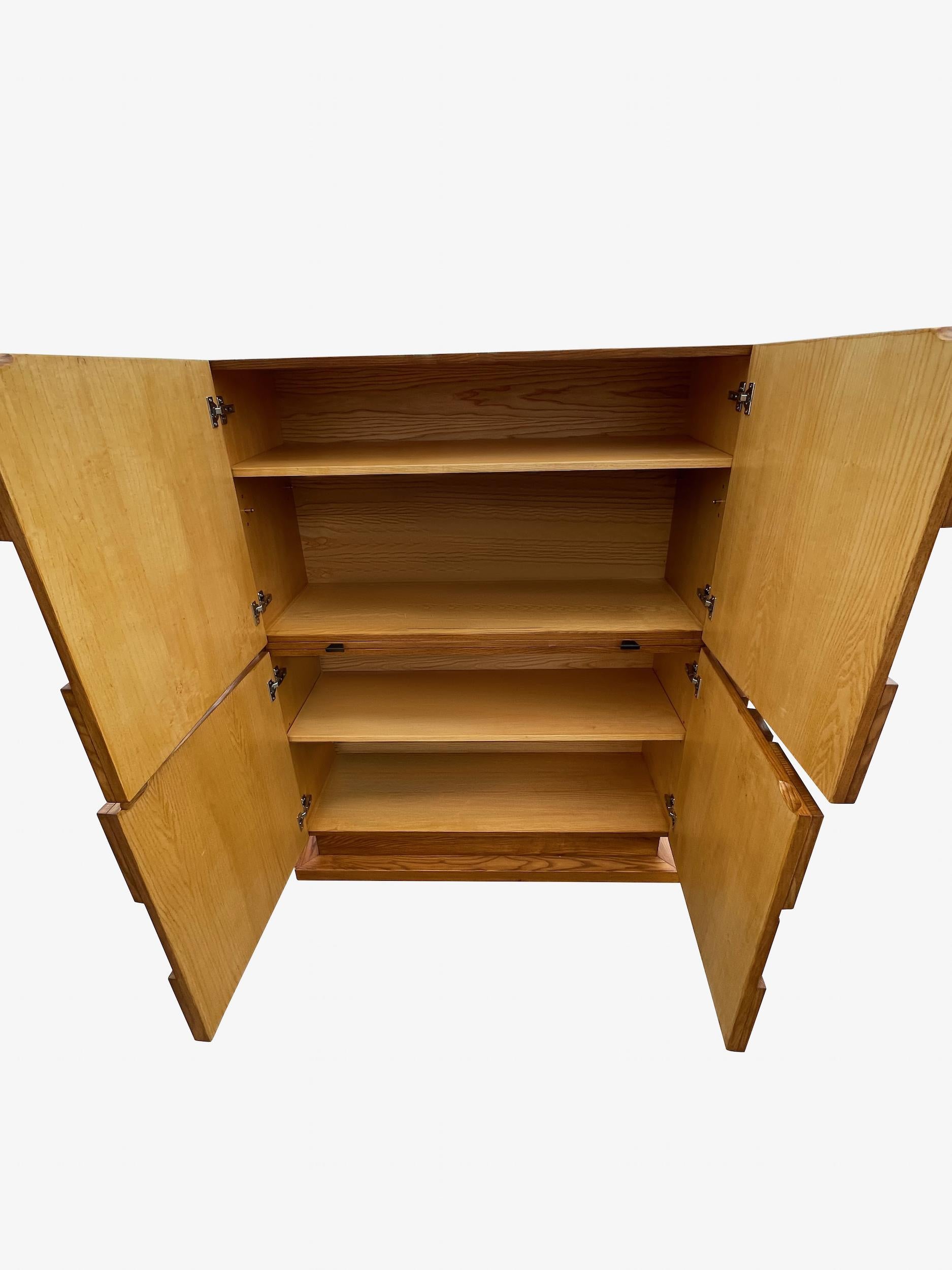 1980's Italian Brutalist design four door cabinet.
Pronounced raised geometric shapes form classic Brutalist design.
Oak wood.
Two inner shelves.
Pull out hidden shelf makes for a desk top ledge.
