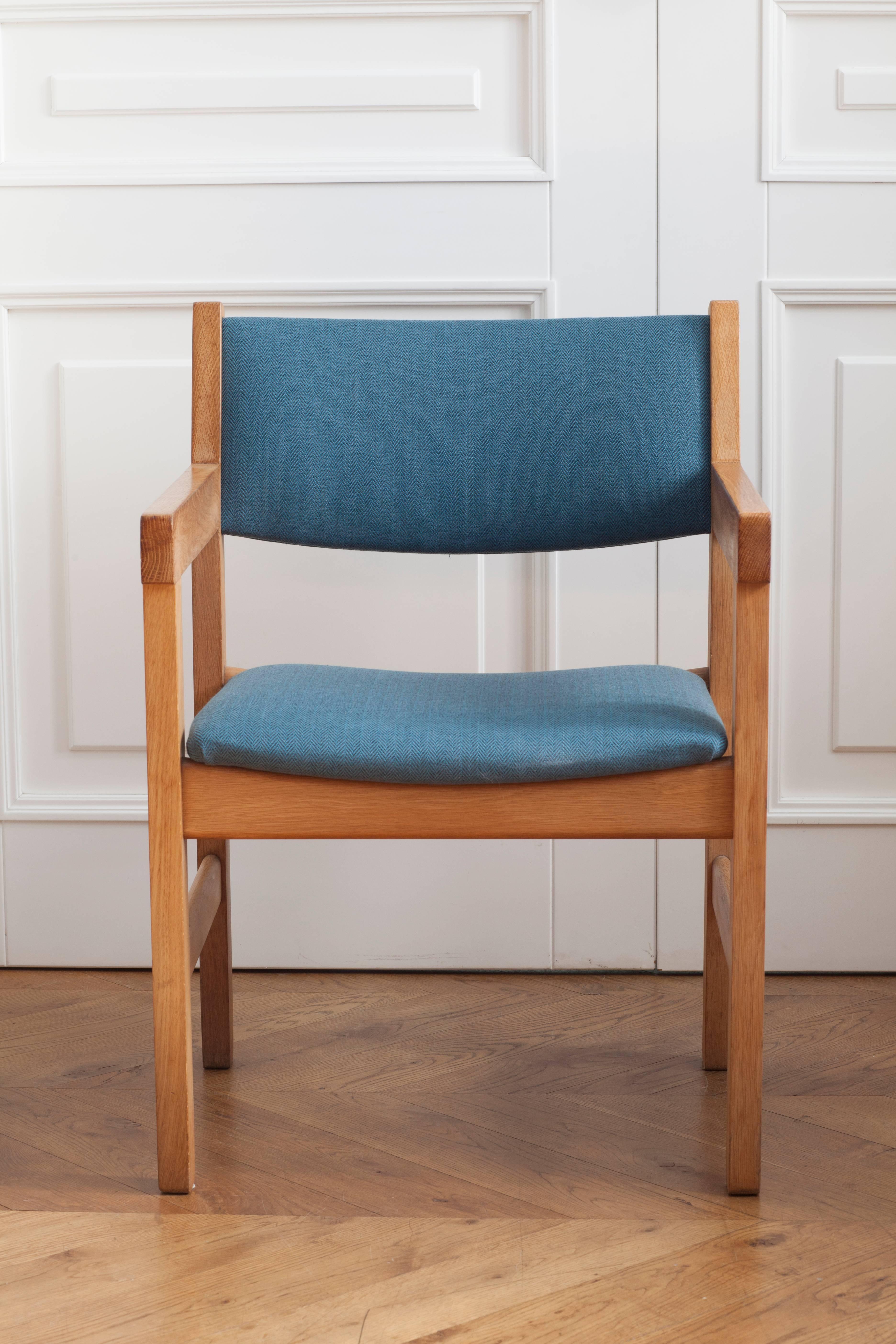 Armchair made of oakwood with designed by Hans J. Wegner. Issued by GETAMA Gedsted in Denmark. Wide backrest and seating are upholstered with a teal coloured fabric. 

Dimensions:
Backrest width 55.3 cm
Seating width 58.5 cm
Total height 79