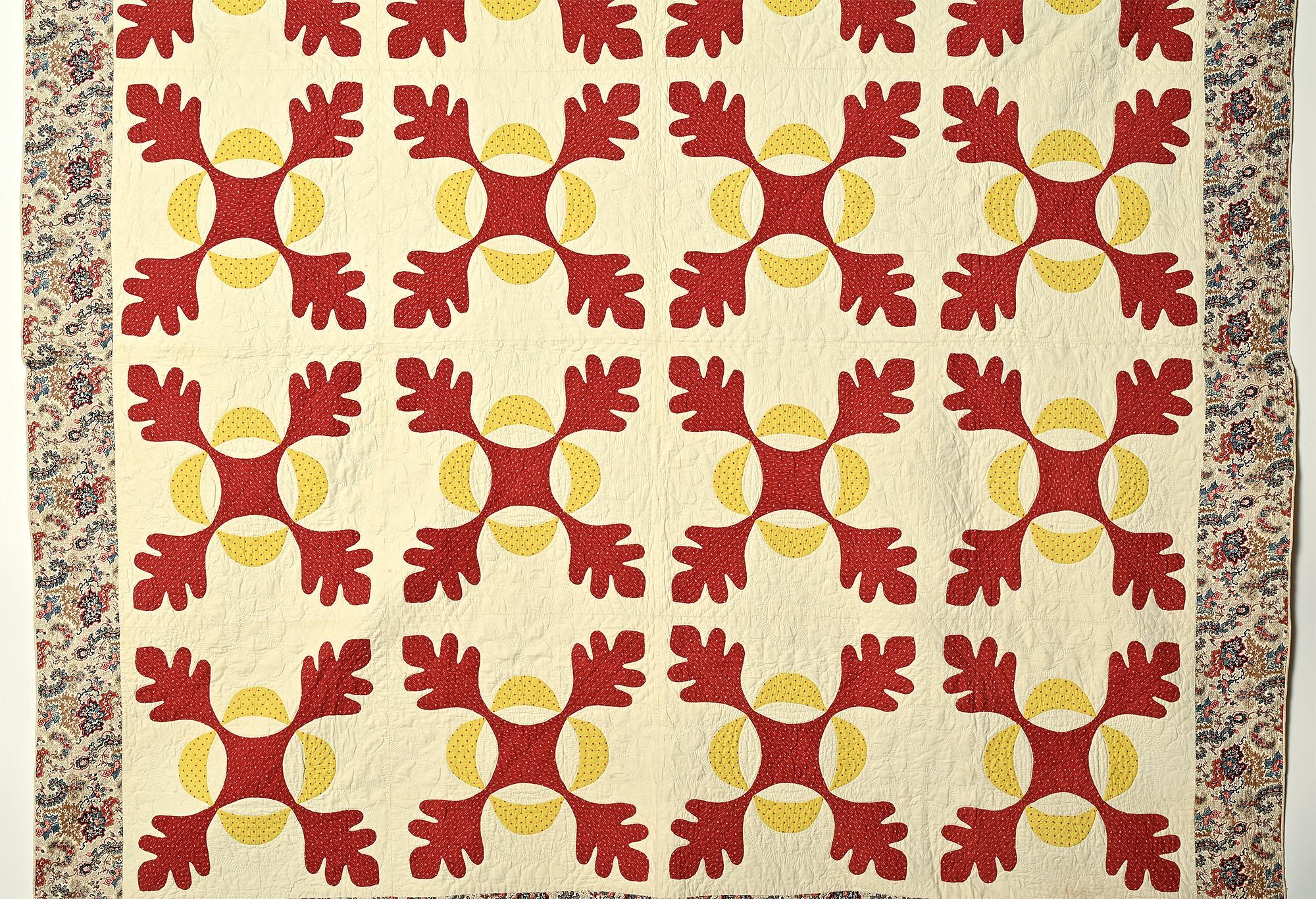 This is a beautifully made version of a tradtional Oakleaf patern quilt. The rust (or brick) color appears to come forward while the yellow recedes. The border is a paisley and floral print that blends perfectly with the interior. The white areas