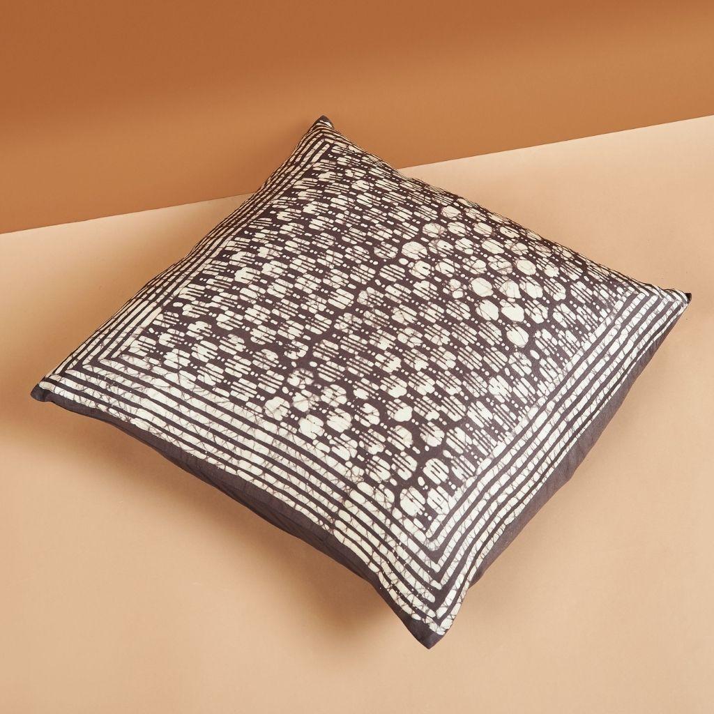 Le coussin en soie Oasis Charcoal est luxueux et exquis avec son imprimé unique en blocs de cire, fabriqué à la main avec soin pour former un motif symétrique et complexe qui se fond pour former un motif géométrique classique. Comme ce coussin est