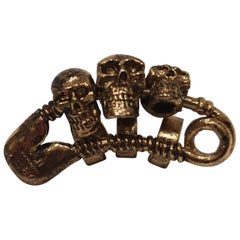 Obey gold tone three skulls pin / brooch