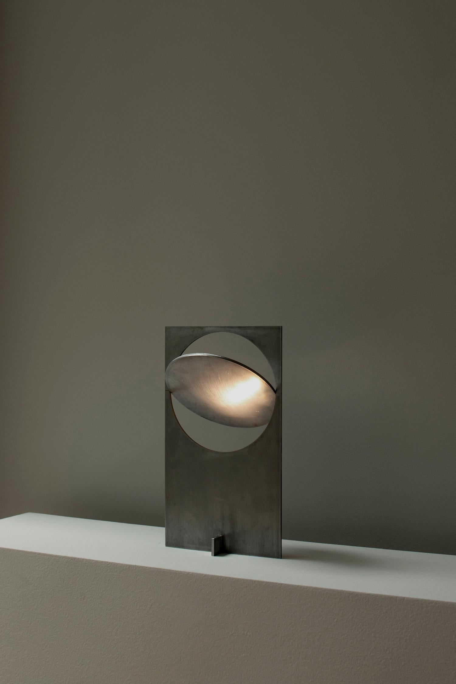 OBJ-01 steel table lamp by Manu Bano
Dimensions: H 38 x W 22 x D 7 cm
Material: hand-polished steel that is sealed with beeswax

All lamps are wired for the US, but voltage converter is available for other countries. 

OBJ-01 is an