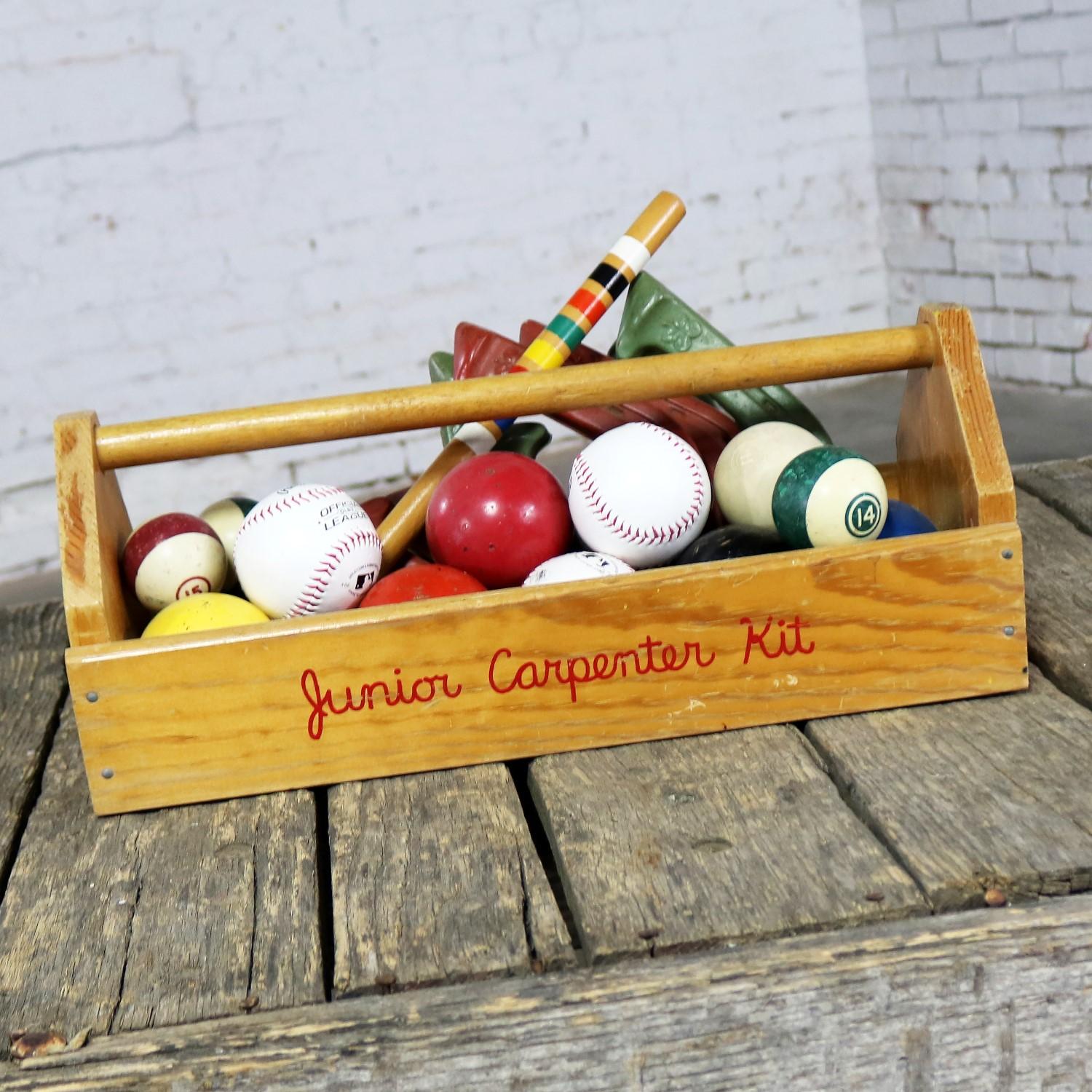 Pièce maîtresse ou objet d'art amusant et fantaisiste composé d'une boîte à outils de Junior Carpenter Kit remplie de boules de billard, de balles de baseball, de balles de hockey sur gazon, de boules de croquet, de chevilles de croquet et de fers à