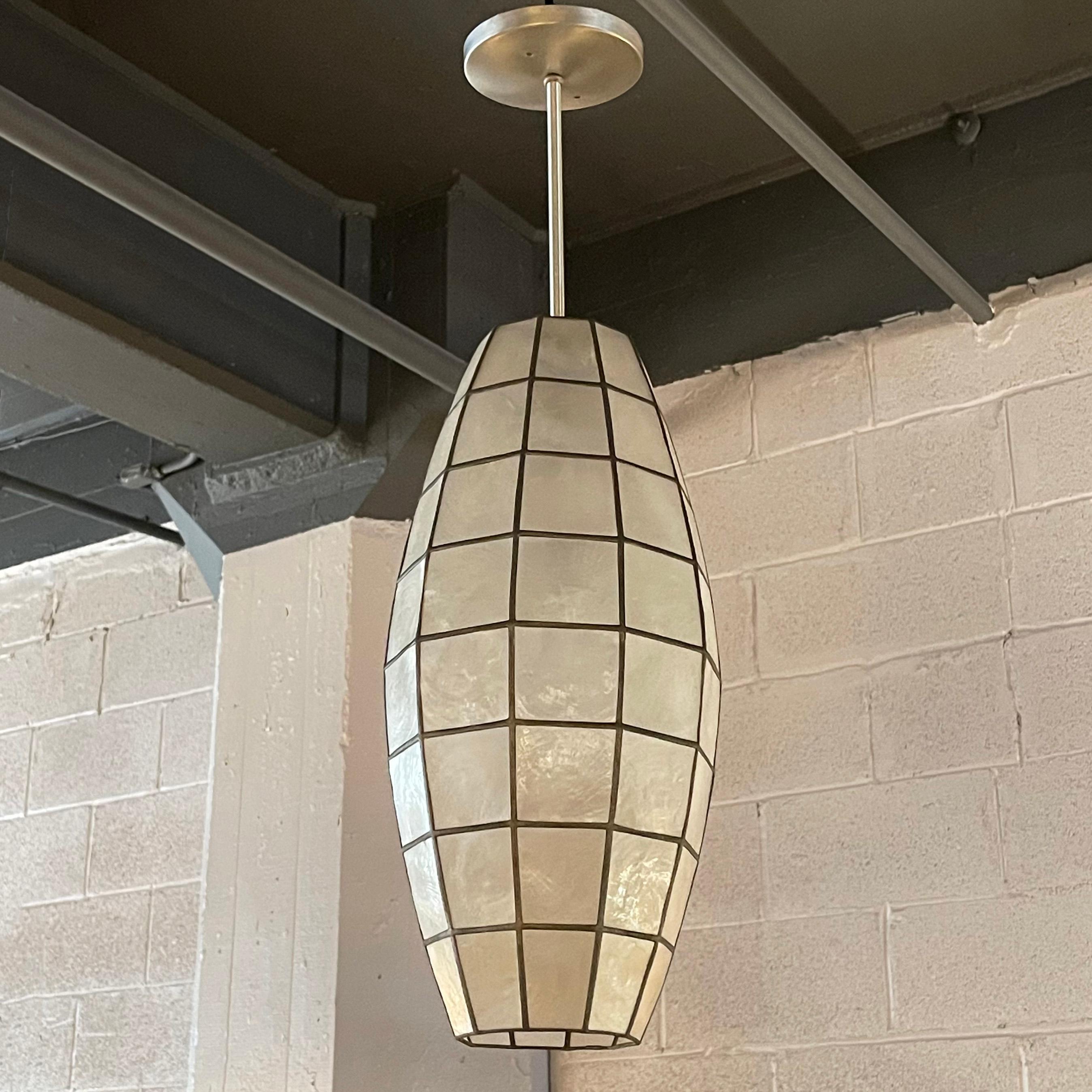 Midcentury, semi flush mount, pendant light features an 18 inch oblong, capiz shell and wrought iron shade on a brushed aluminum pole and canopy.