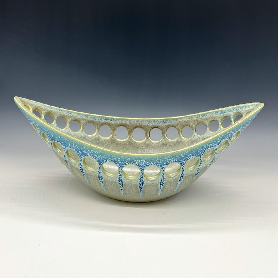 Inspired by organic contemporary design, this pierced oblong bowl is wheel thrown, distorted and hand pierced stoneware with a satin glaze. Small holes are created when the clay is still wet and then each hole is painstakingly enlarged and smoothed