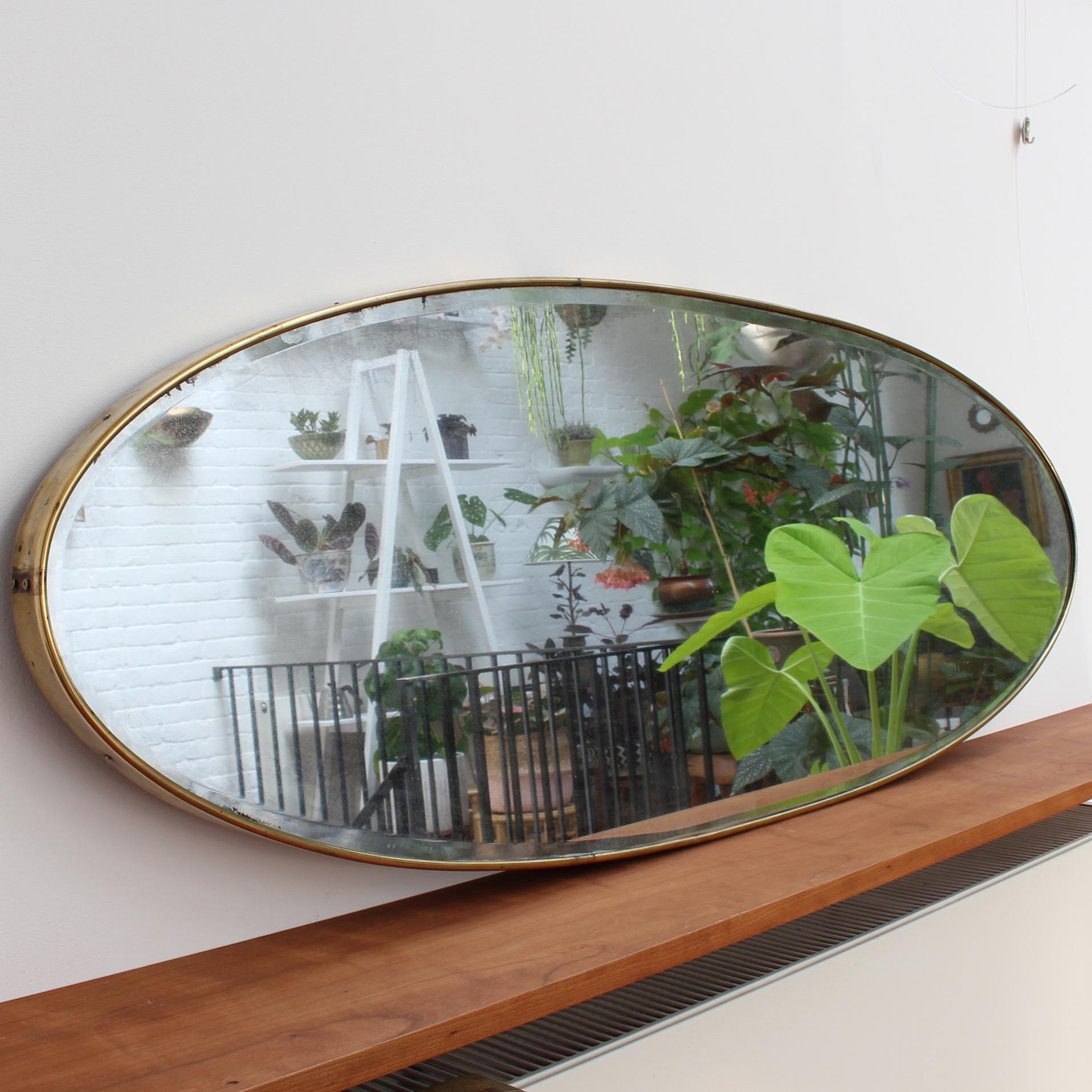 Oblong Italian wall mirror with brass frame, circa 1950s. The mirror is beautifully oblong-shaped with classic detailing. Always elegant and distinctive in a modern Gio Ponti style. Configured for a horizontal hanging but may be modified to be hung