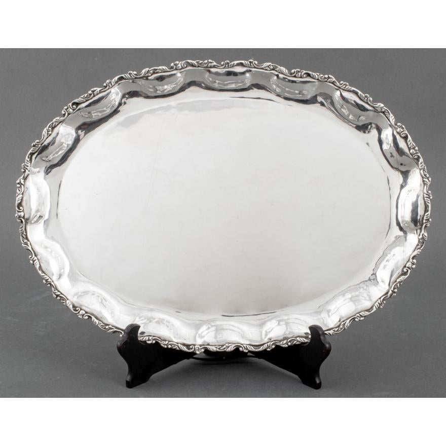 Eleva tu colección de bar y vajilla con esta exquisita Bandeja Oblonga Mexicana de Plata de Ley. Meticulosamente elaborada a mano, esta bandeja presenta diseños foliados grabados a mano y repoussé que añaden un toque de sofisticación y arte. La