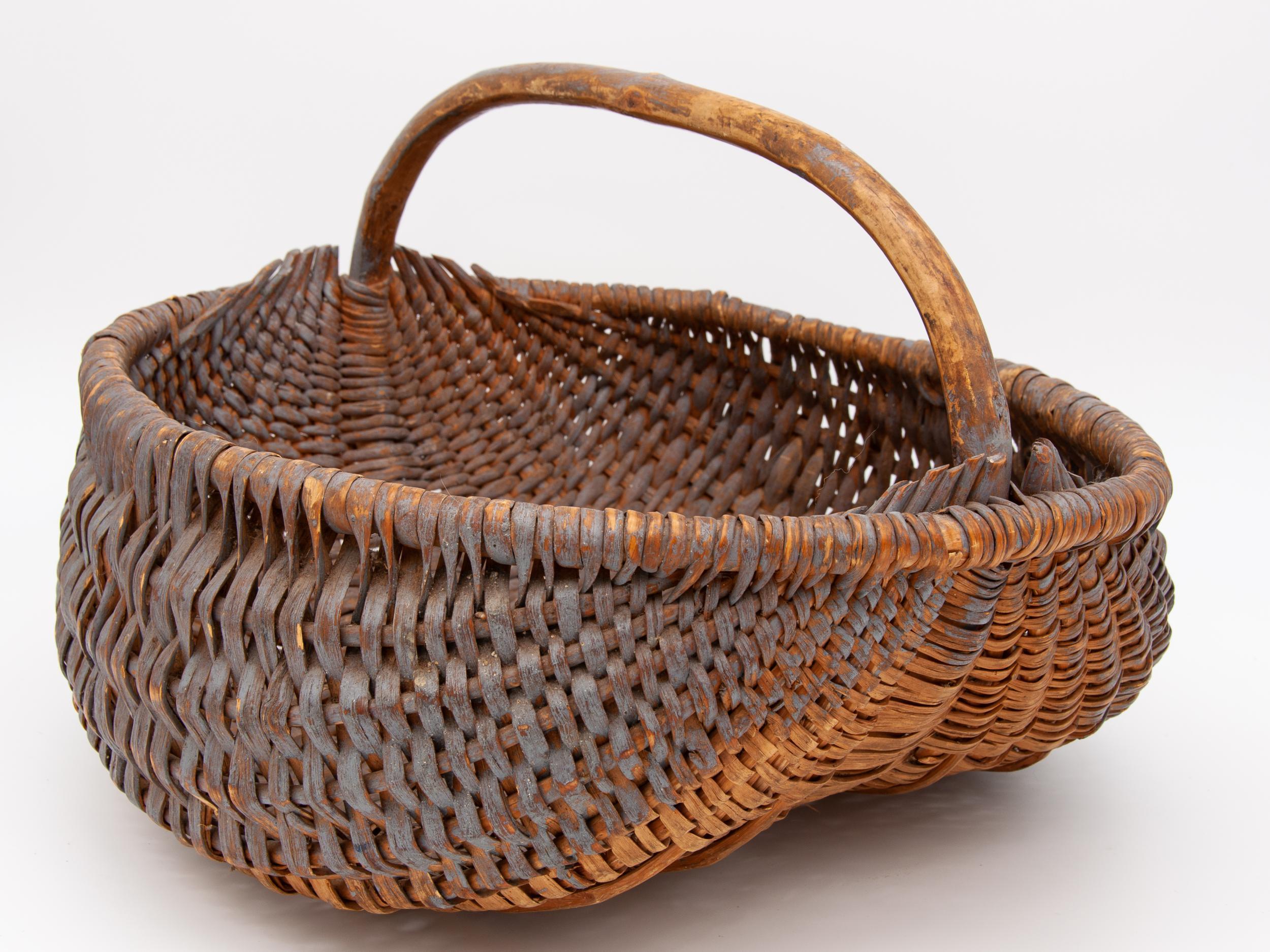 Panier Vintage avec une belle forme et une anse courte, robuste et solide. Le panier a été peint précédemment et a été utilisé depuis, ce qui explique la patine usée de la peinture et du bois. Idéal pour le stockage ou la décoration.