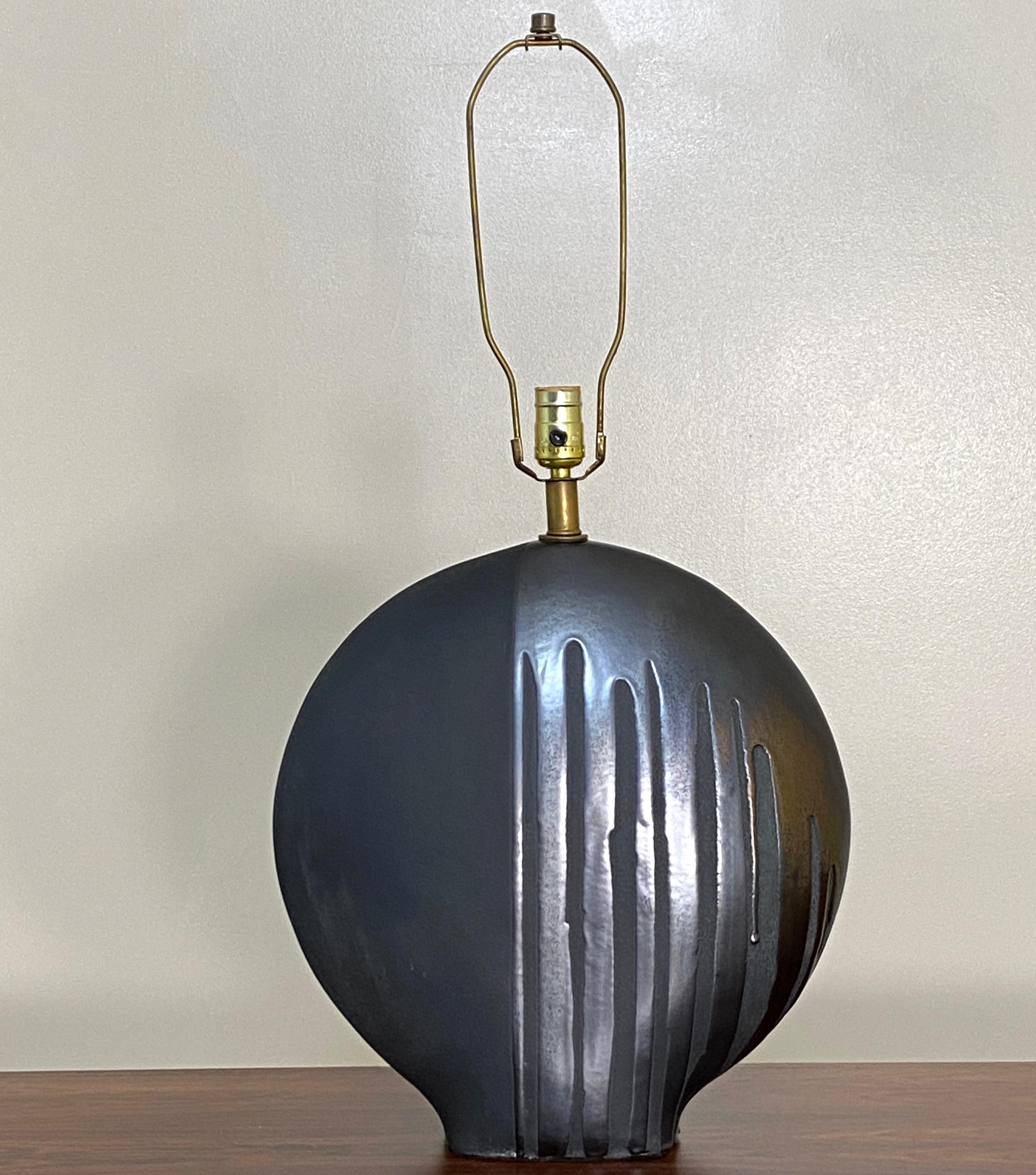 Disc shaped table lamp by Markel. Obsidian glaze over matte finish gives this lamp a very unique appearance. The round nature of a disc with support base to it with its considerable weight make this a lovely designer lamp. In excellent condition