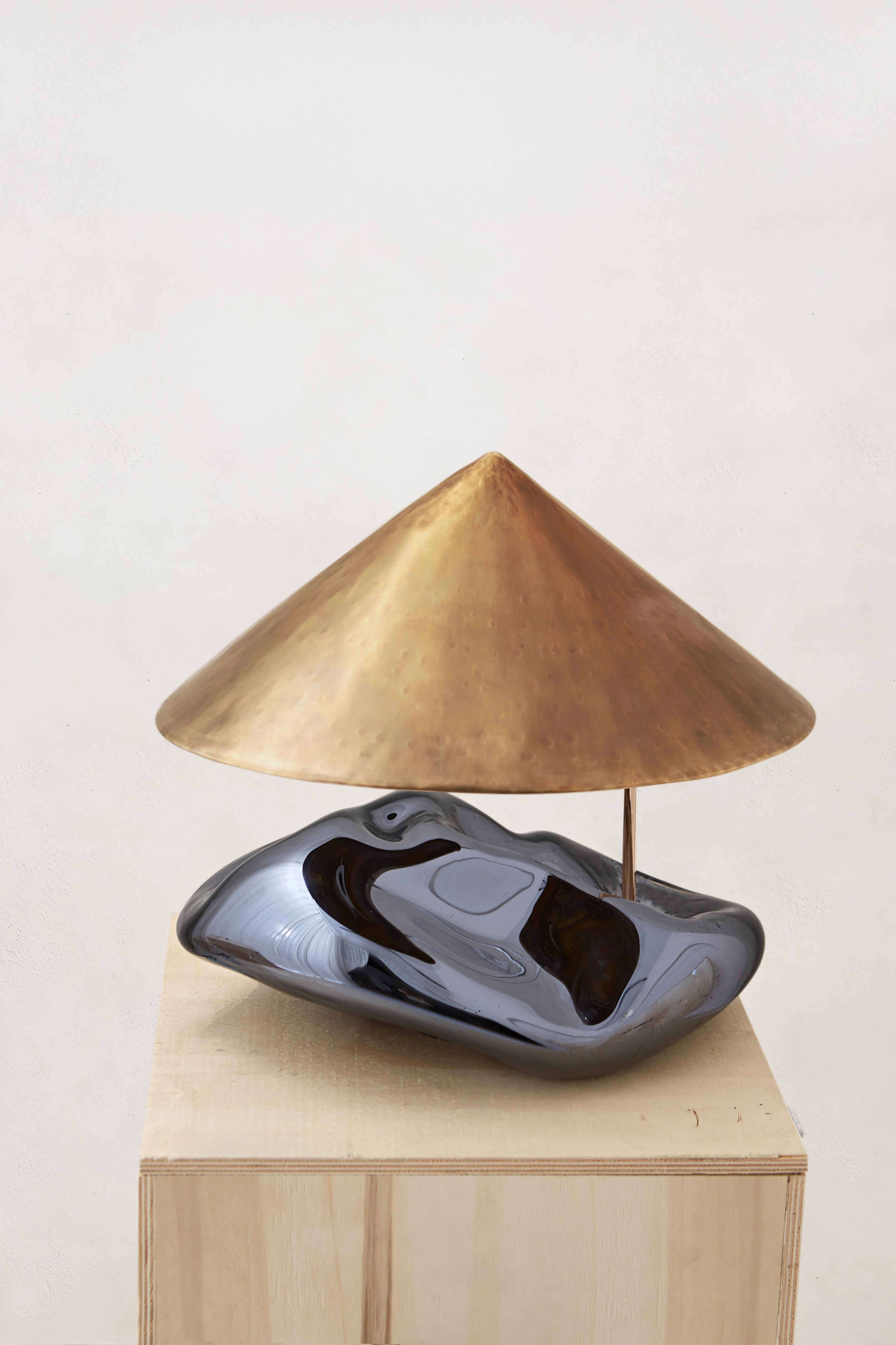 La Collection OBSIDIAN LAMP met en valeur deux matériaux principaux : le verre et le cuivre. Le verre, associé au miroir, agit comme un diffuseur et un réflecteur de lumière, rappelant la façon dont les pierres d'obsidienne étaient polies et
