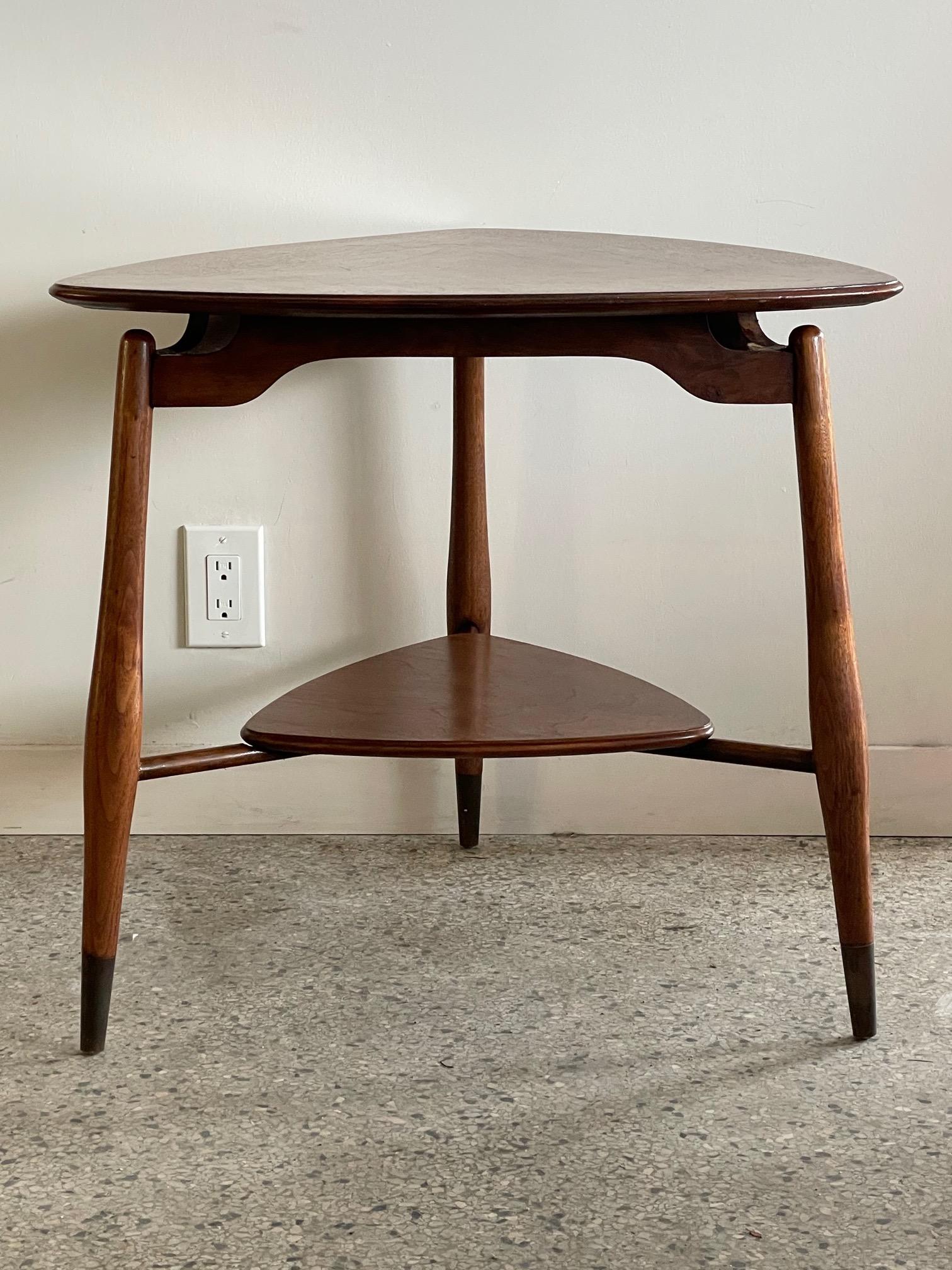An occasional table in walnut by John Widdicomb. Floating top with lower shelf, brass sabots on legs.