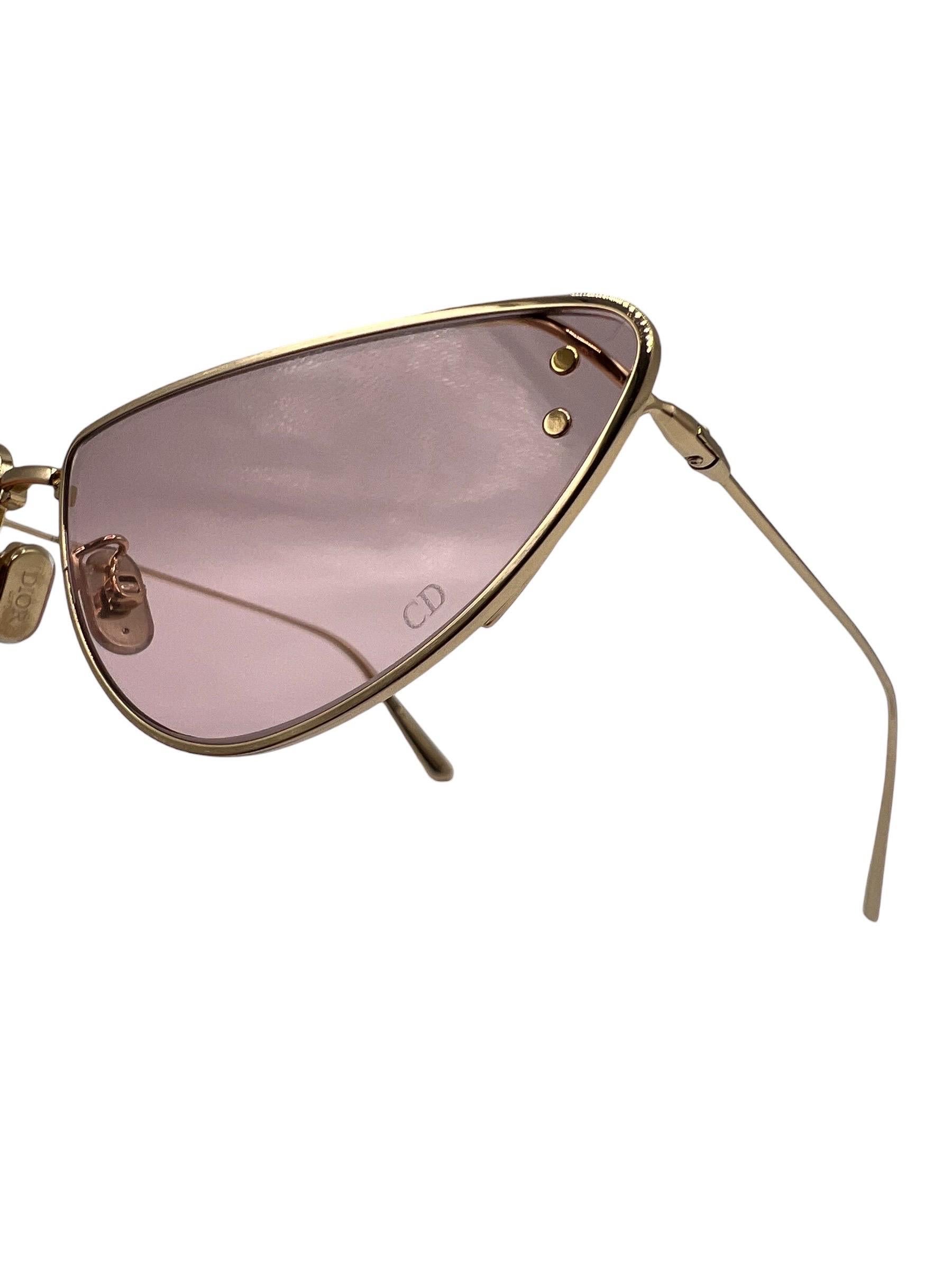 Occhiali firmati Christian Dior, realizzati in metallo placcato oro nella forma irregolare a farfalla. Caratterizzati da lenti rosa e una struttura sottile biforcata, con logo ”CD” impresso su una delle lenti. Munite di custodia, si presentano in