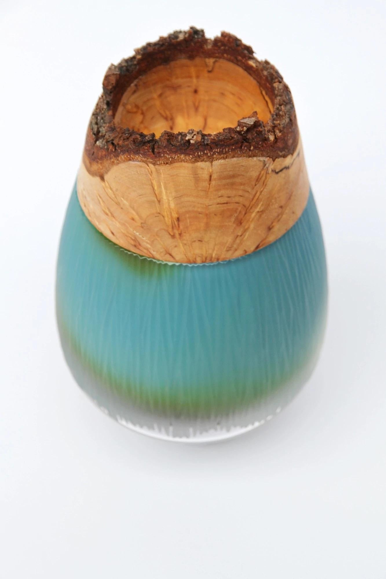 Ocean Frida with fine cuts stacking vessel, Pia Wüstenberg
Dimensions: D 13 x H 20
Materials: cut glass, wood
Available in other colors.

With its sculpted glass topped by Curly Birch, Poppy is an exquisite vessel. This delightful piece finds