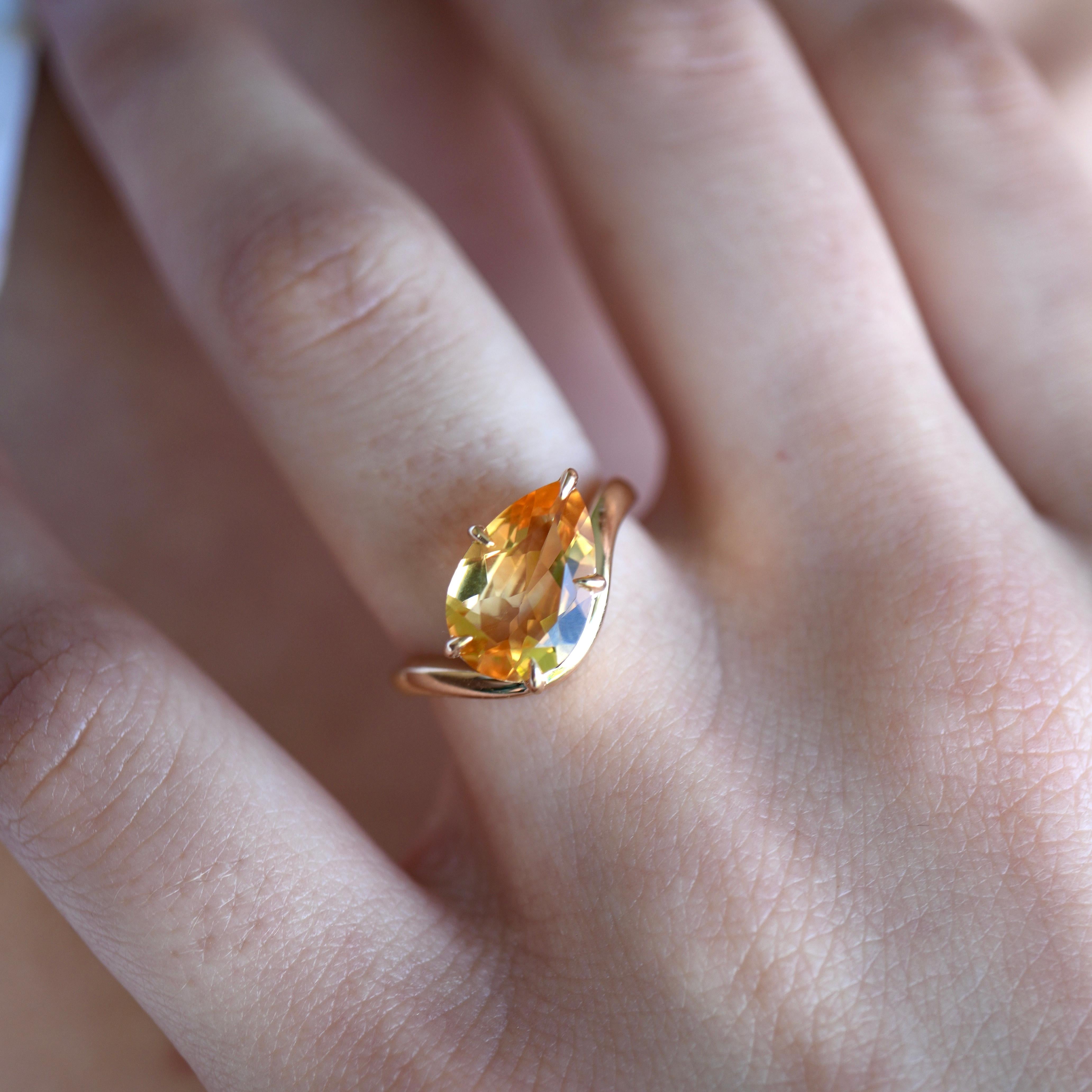 This East-West ring centers on a glowing citrine, its golden hue reminiscent of sunlight dancing across a tranquil shoreline. Set in 14K yellow gold, the gem is held in a graceful wave-inspired frame that adds a soft sense of movement and balance to
