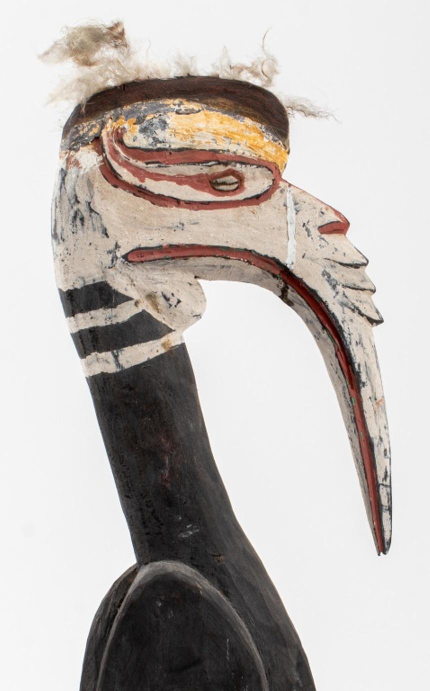 Oceania, Papua New Guinea, hand-carved and polychrome painted wooden animalier statue depicting a hornbill bird, with inset cowrie shell eyes and mounted with feathers to crown.

Dimensions: 26