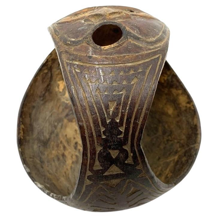 Tribal carved cup with handle with incised and carved design. Possibly from the Abeam People in the Sepik Region of New Guinea,  the cup has overall meandering incised design and a strongly carved face on the handle center with open mouth as if