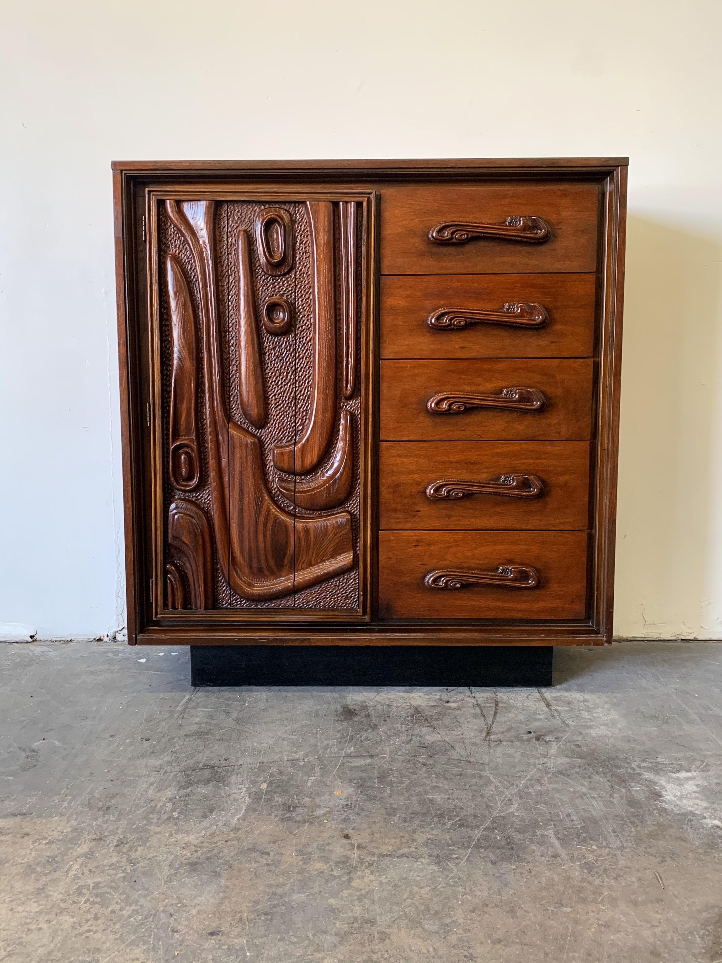 This fantastic lacquered sculpted walnut 'Oceanic' highboy dresser cabinet by Pulaski Furniture Corporation, circa 1969 which perfectly encapsulates the California surf mentality of the 1960s and 1970s, making this piece a highly sought after design