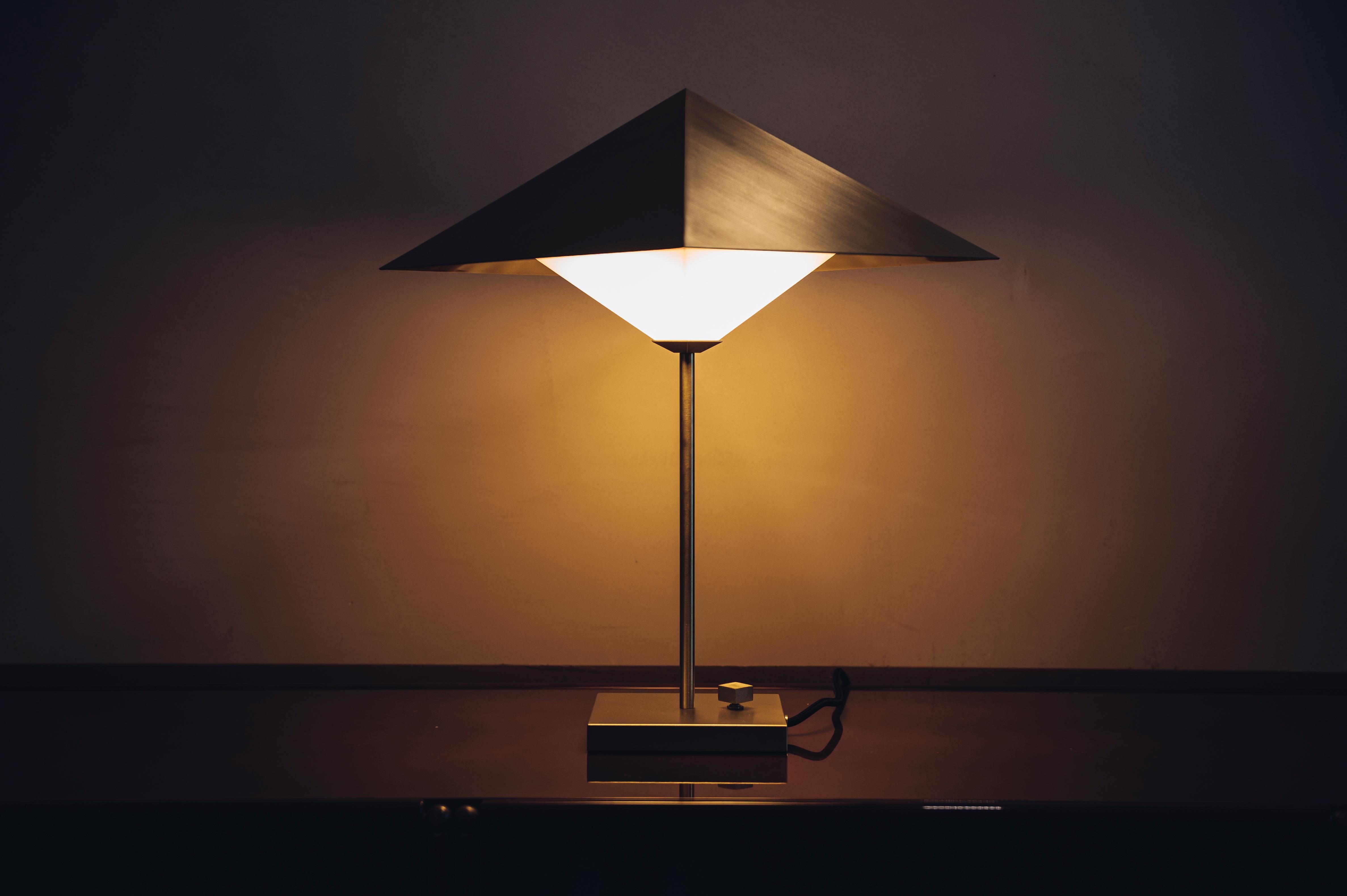 The dominant feature of OCTA’s table lamp is its square pyramidal shade. The acute angles of the pyramid are emphasized by the brushing direction, which remains consistent in the base and rotary switch.

The pyramid’s cavity reveals a set of