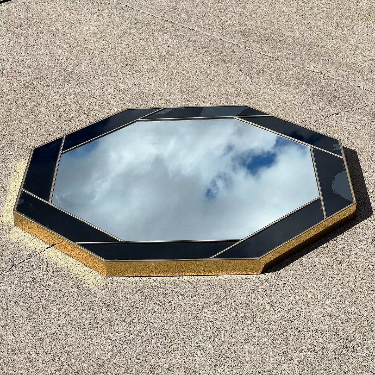 Miroir de forme octogonale avec un cadre acrylique en laiton et noir. Le motif ressemble à l'ouverture d'un appareil photo. Probablement années 1980. 36,5