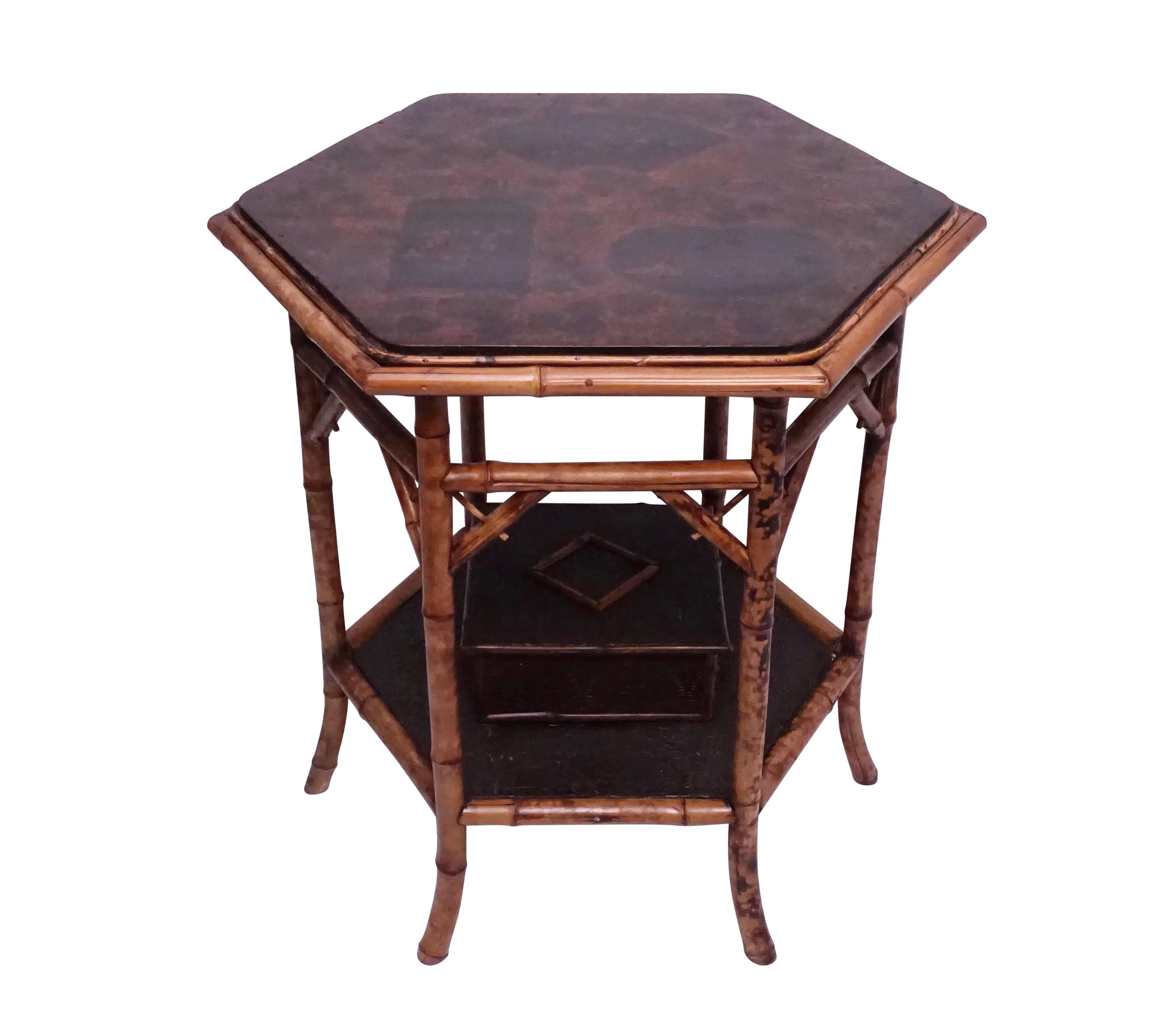 Highly unusual octagonal shape bamboo table with lacquered top and having a lower shelf with an affixed box. The top has three geometrical shapes with scenes of mountains, birds and flowers, the lower shelf and box with embossed brown paper board,